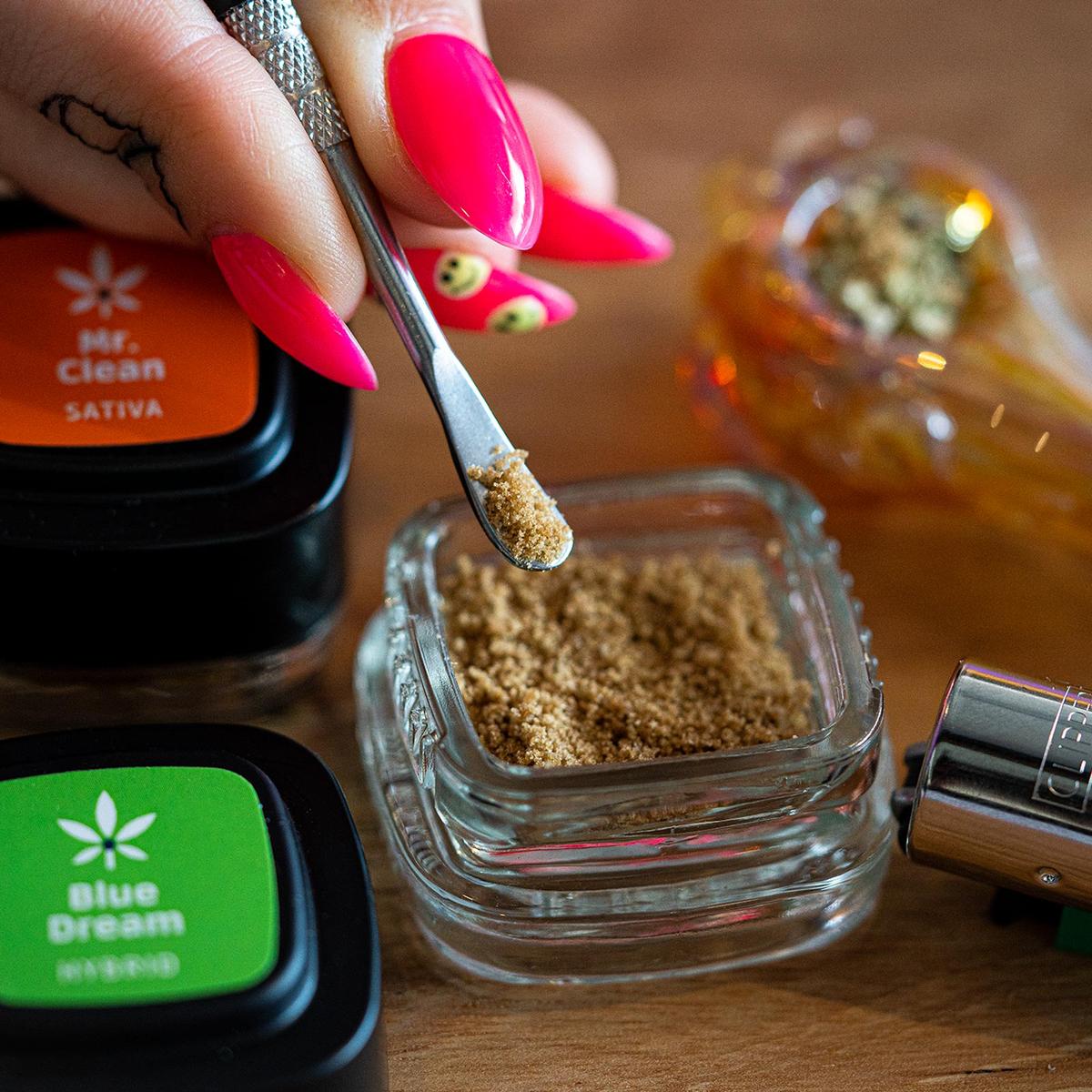 Bubble hash in a glass jar beside labeled nuEra concentrate lids