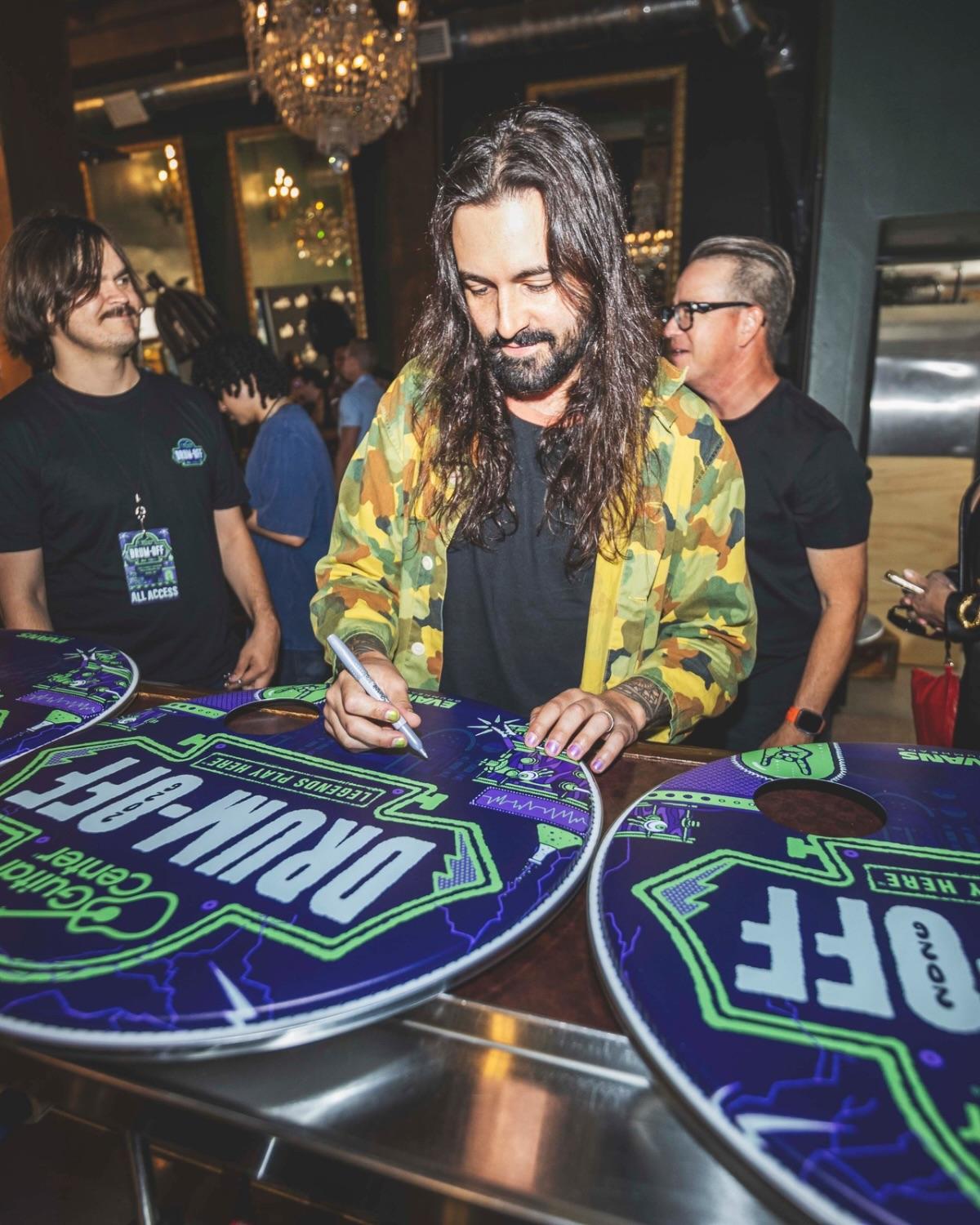 Oversized Drum-Off drumheads being signed at a table