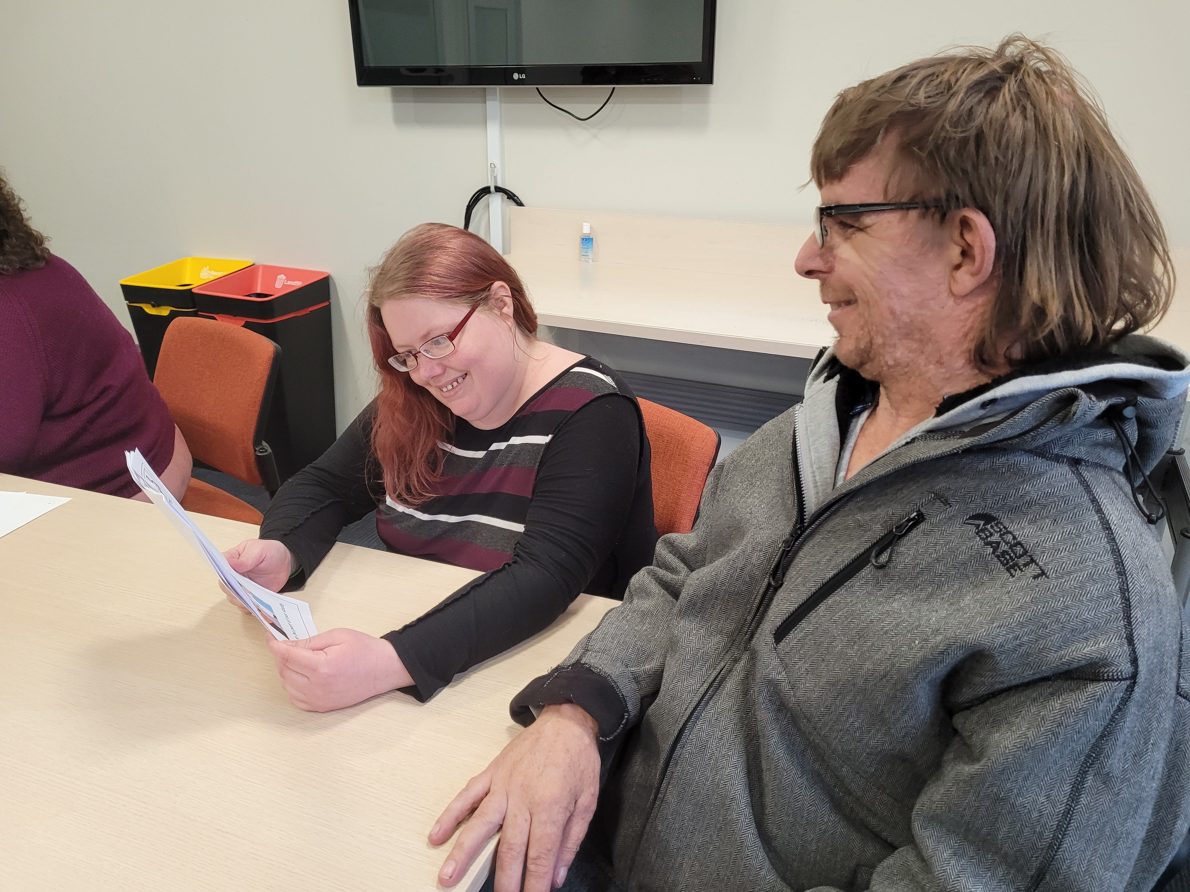 Two people sitting at a table looking at an Easy Read document.