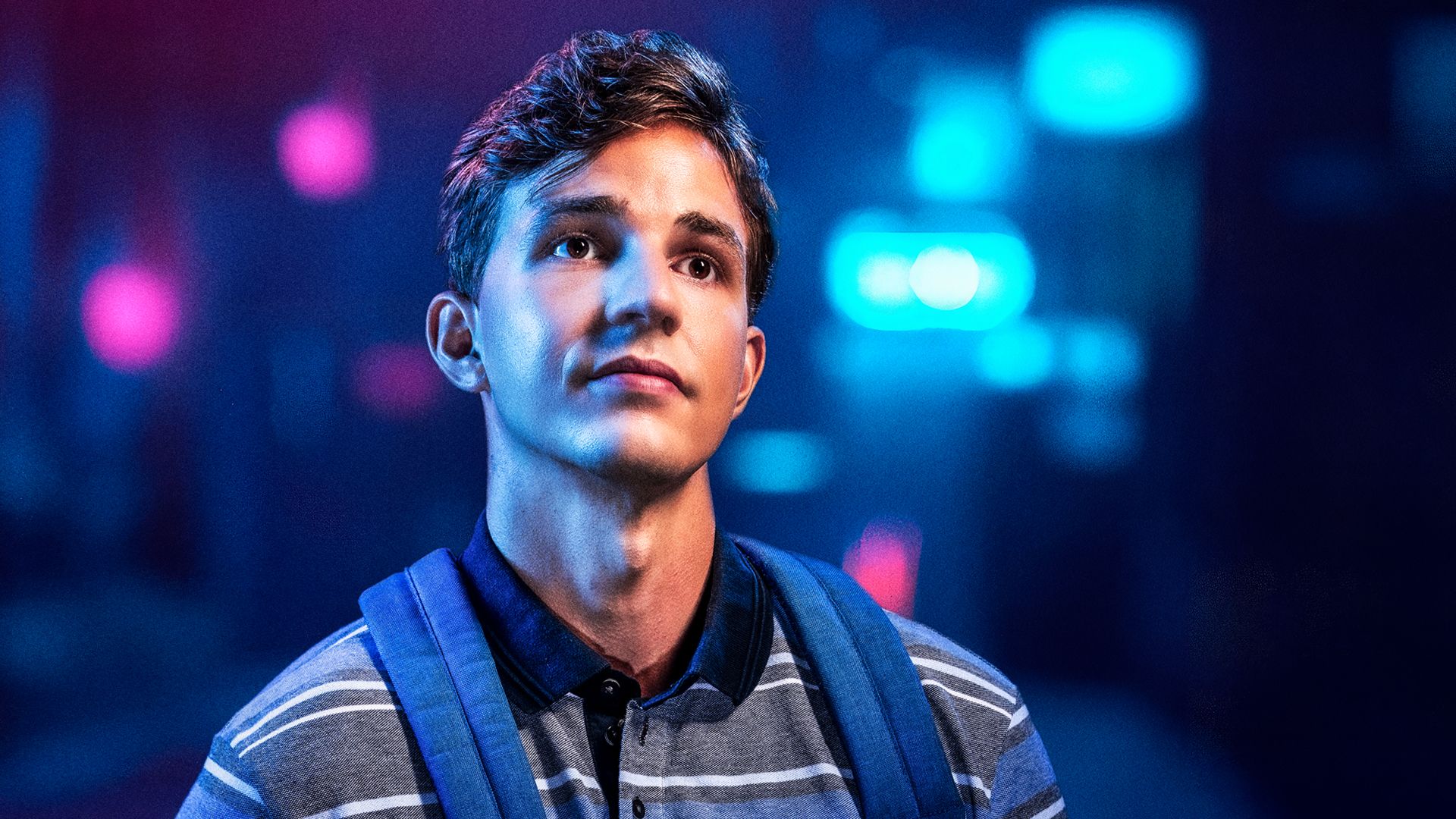 Manér för Dear Evan Hansen 2026. Porträttbild av kille med ryggsäck som blickar ut med sorgsen blick. Bakgrunden är mörk med ljus som glimtar i blå och rosa färger.