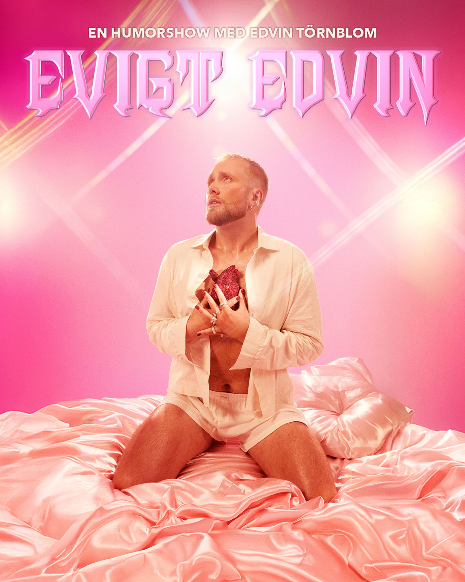 Manér bild för Eviga Edvin med Edvin Törnblom. Han sitter på en säng med siden lakan iklädd siden pyjamas shorts och en skjorta. Han håller i ett diamant hjärta. Hela bilden går i rosa färger.