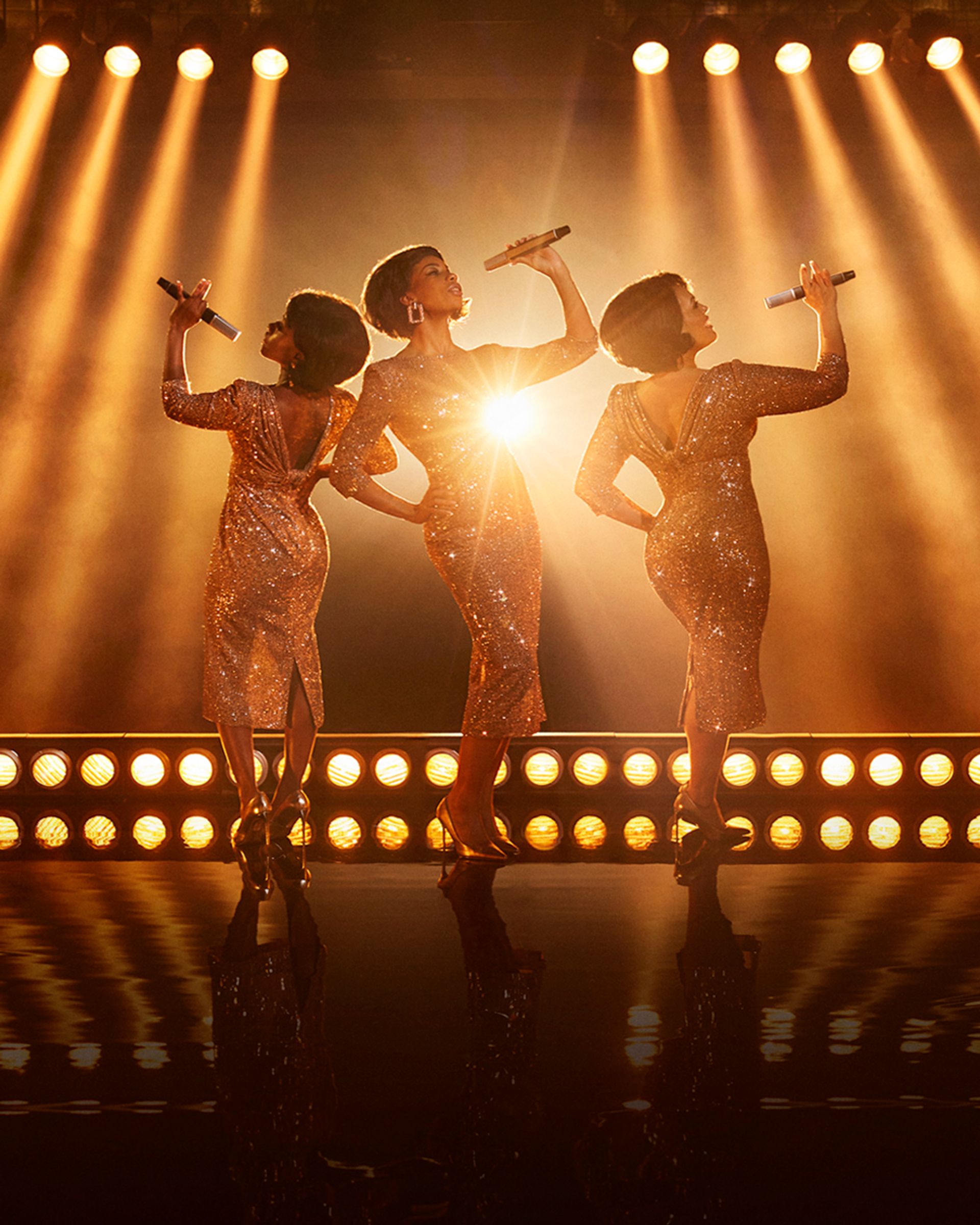 Dreamgirls The Musical manér. Tre tjejer som står i glittriga klänningar.