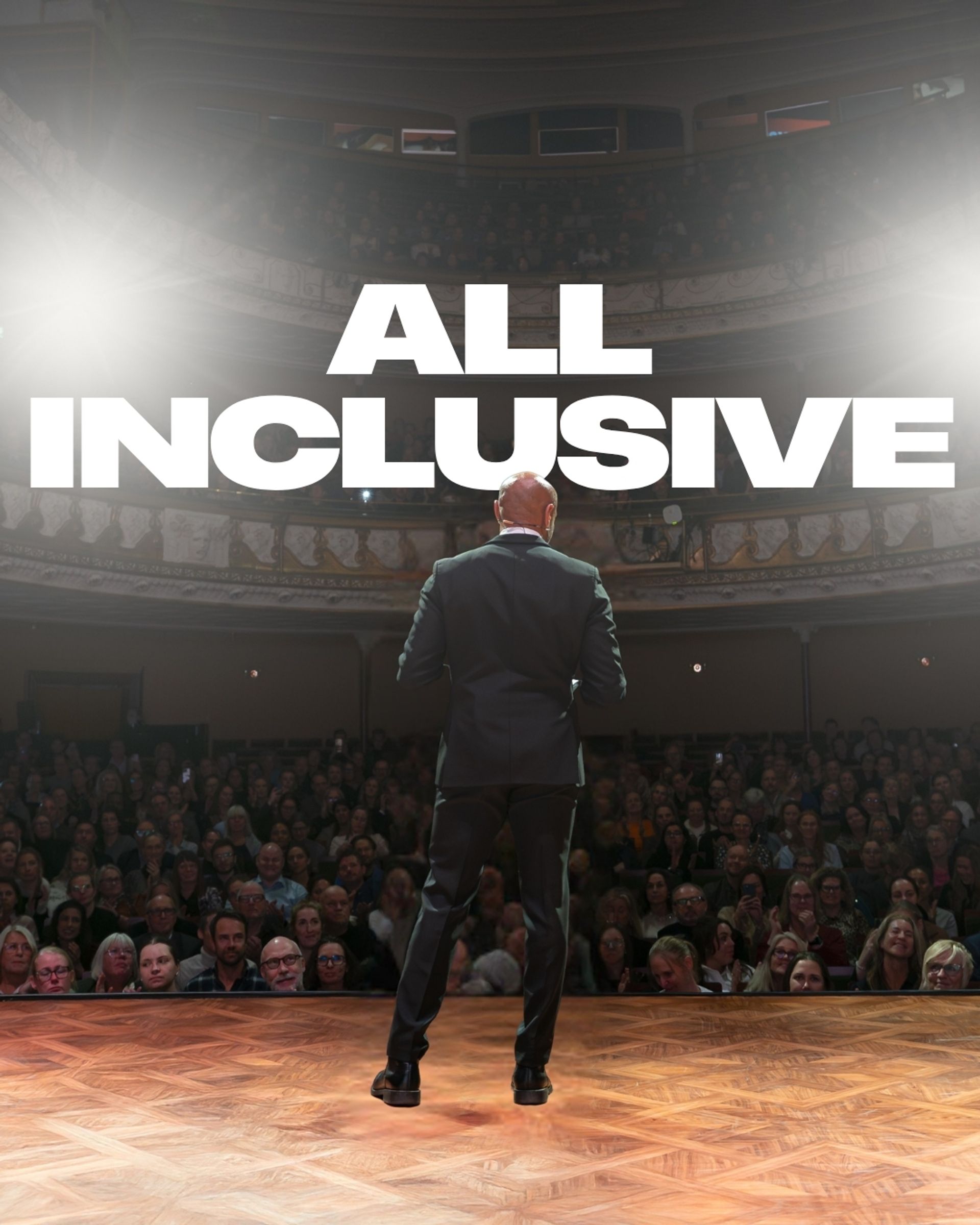 Manér för All Inclusive - Aaron Kroon med gäster. Aaron står på scen med kostym och tittar ut över en publik. Bilden är tagen bakifrån