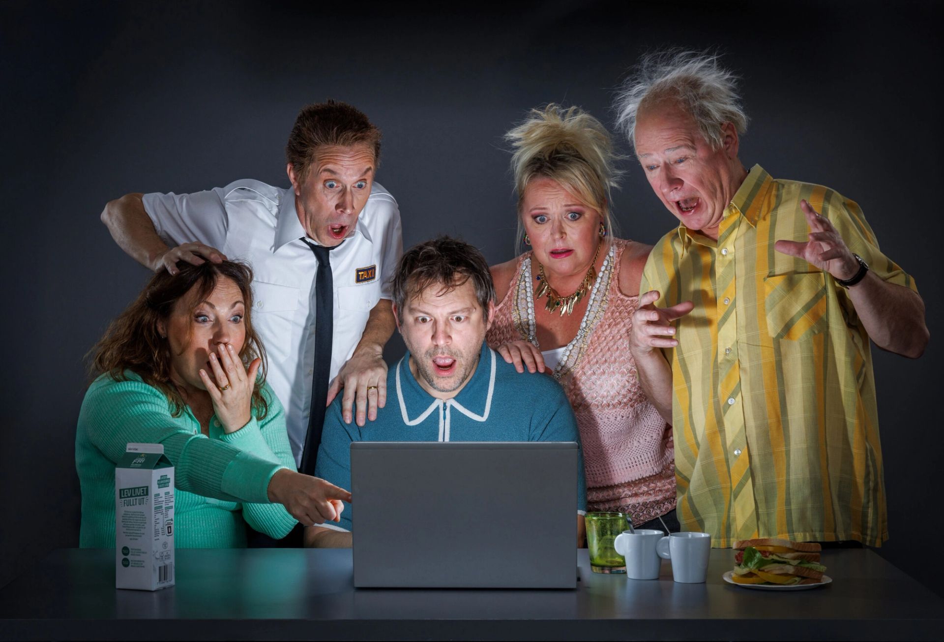 Pressbild för ”Fångad på nätet” med fem skådespelare runt en bärbar dator, reagerande med starka uttryck av förvåning.