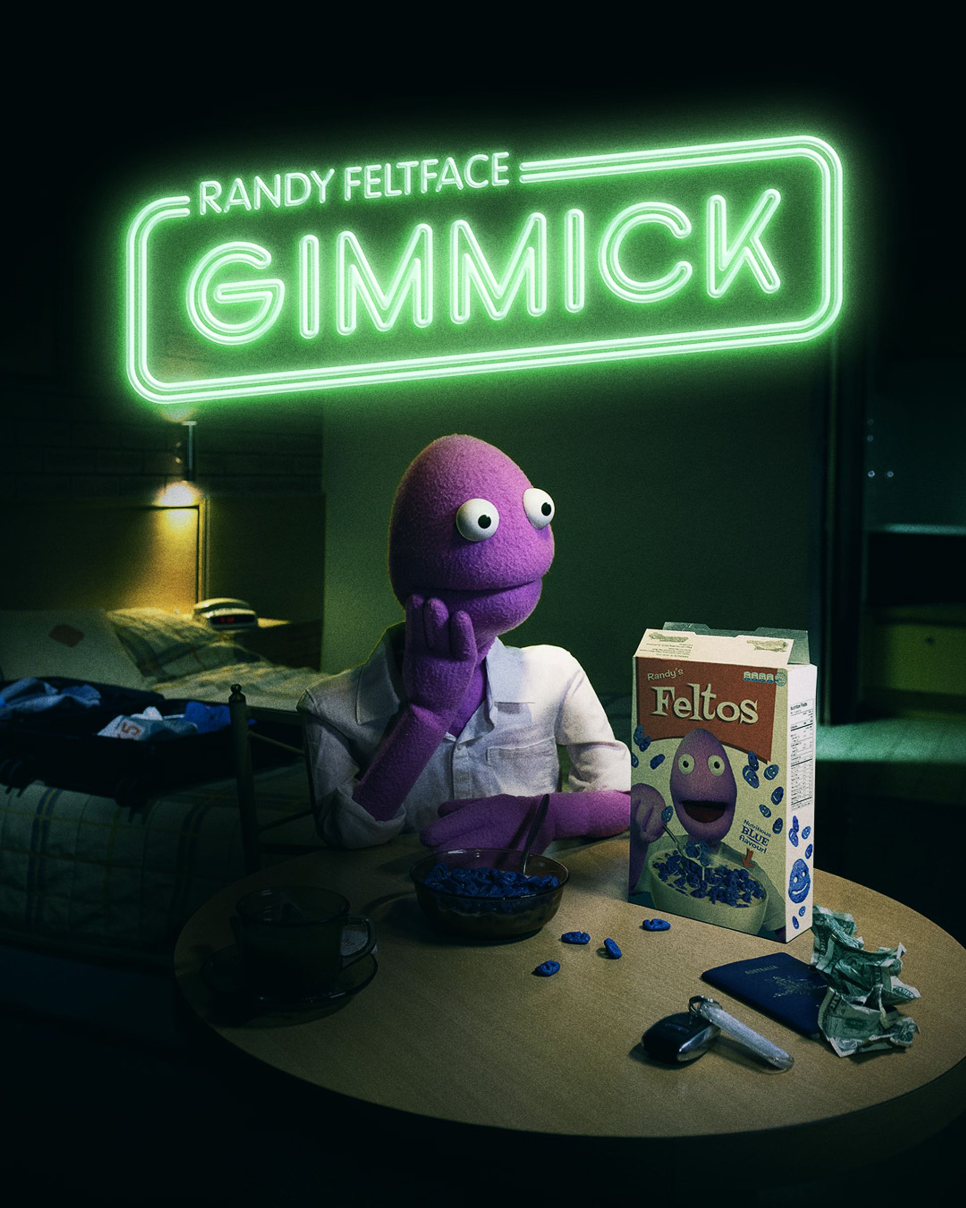 Manér bild för Randy Reltface föreställning Gimmick. Dockan Randy sitter i en lägenhet vid ett köksbord med en mörk bakgrund.