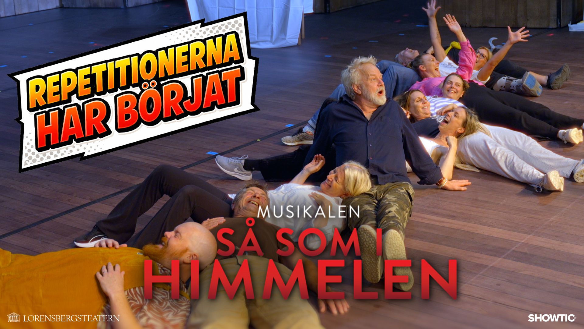 Thumbnail - Så som I himmelen kollationering video. Flera ur ensemblen ligger i ett sicksack mönster på golvet och skrattar.