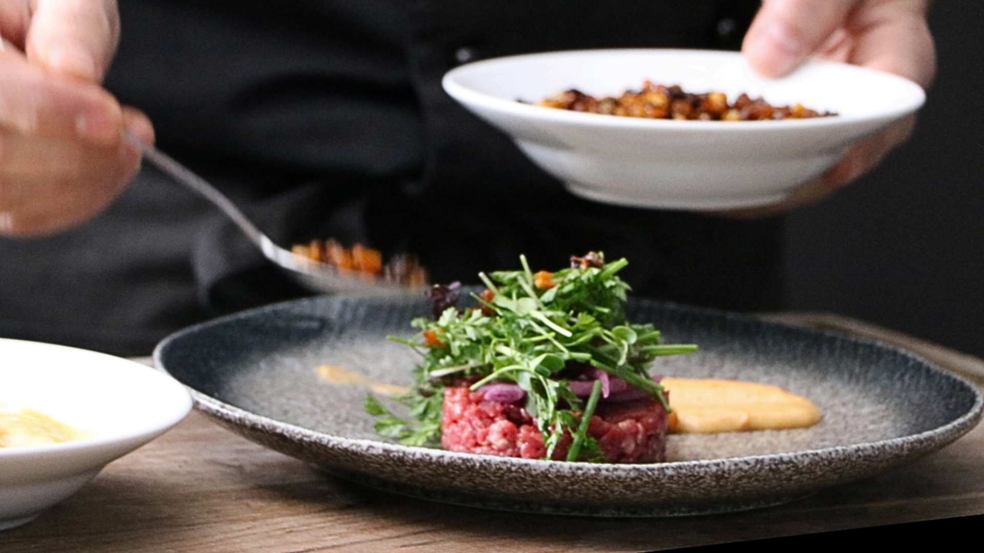 en kock lägger upp mat på en tallrik.