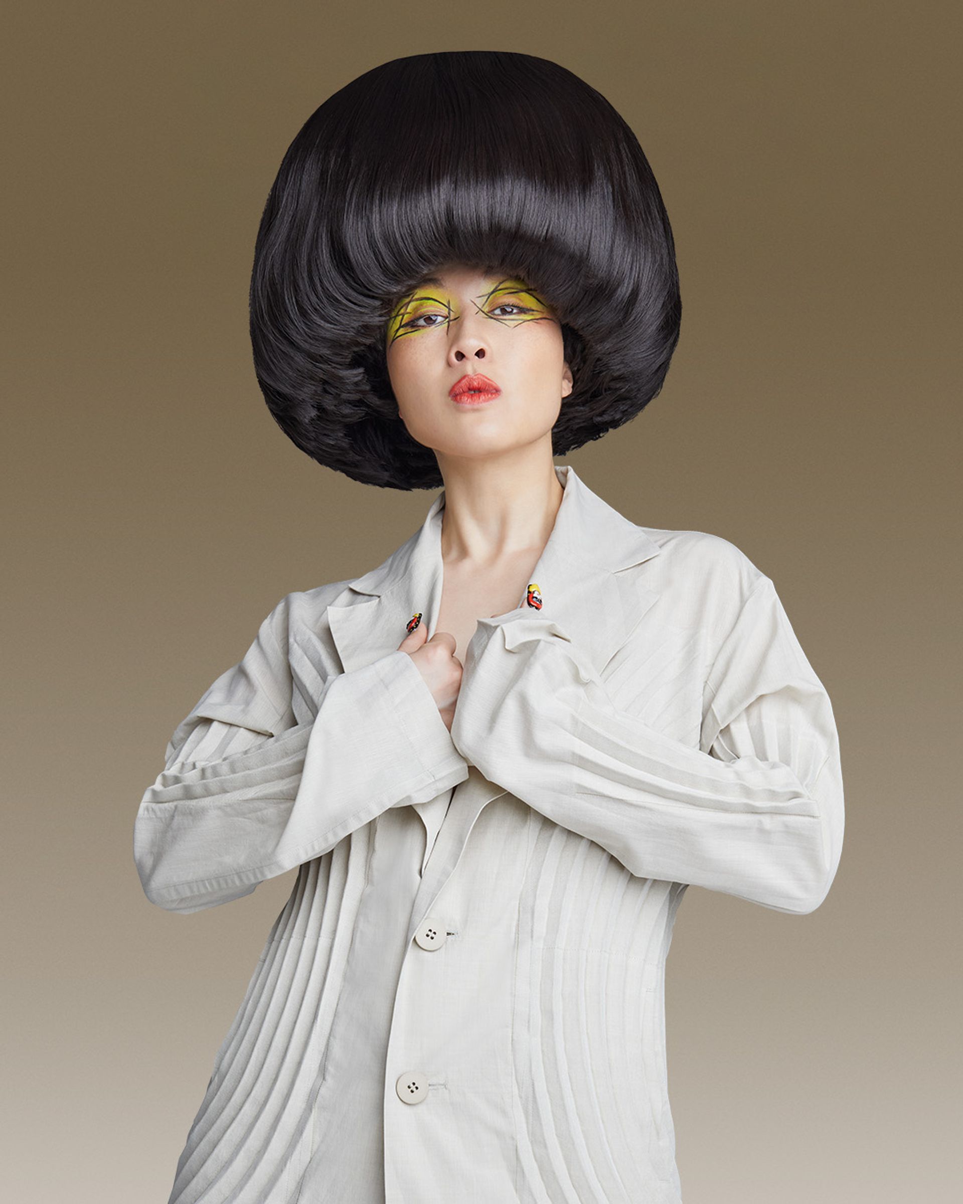 Porträtt av Atsuko Okatsuka i vit kostym, med en stor svart rund frisyr och färgstark ögonmakeup mot en brun bakgrund. The Big Bowl Tour spelas på China Teatern i Stockholm den 16 februari 2027.