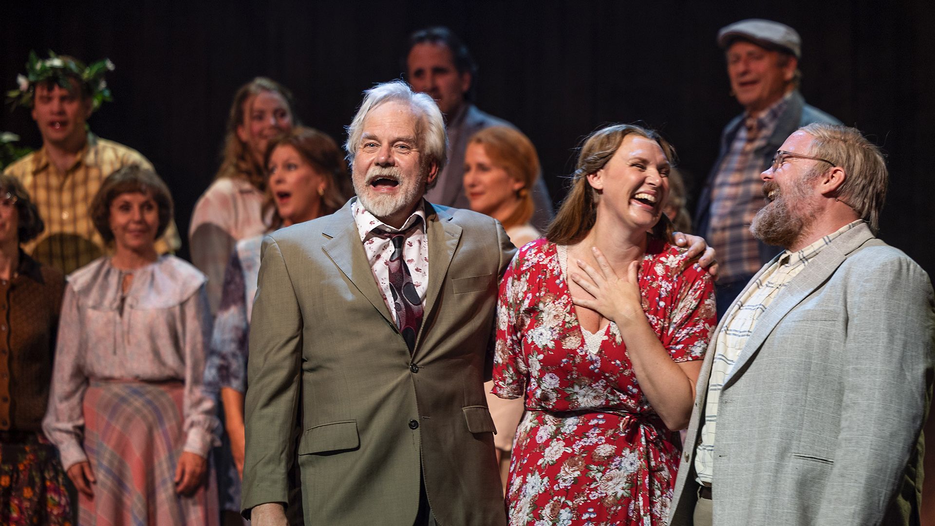 Scenbild från musikalen Så som i himmelen på Lorensbergsteatern i Göteborg. Peter Apelgren, Sanna Nielsen och Henric Joneskär står längst fram, skrattar och sjunger tillsammans med ensemblen i bakgrunden.