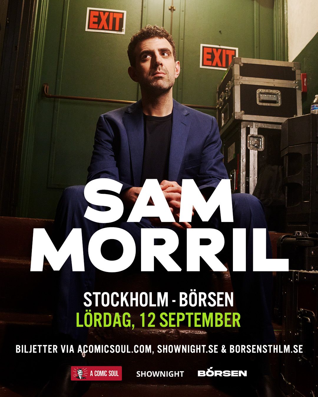 Sam Morril standup show – komiker i blå kostym bakom scen med EXIT-skyltar, porträtt inför liveföreställning