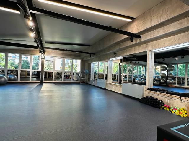 A group-class hall with a rubber floor, mirrors and fitness balls