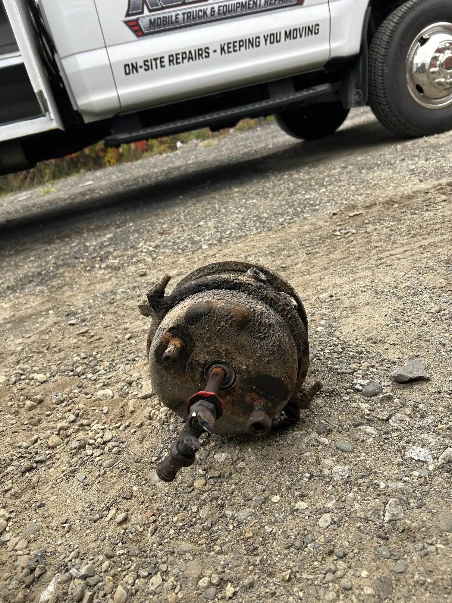 Old brake chamber removed and set on the gravel beside the truck
