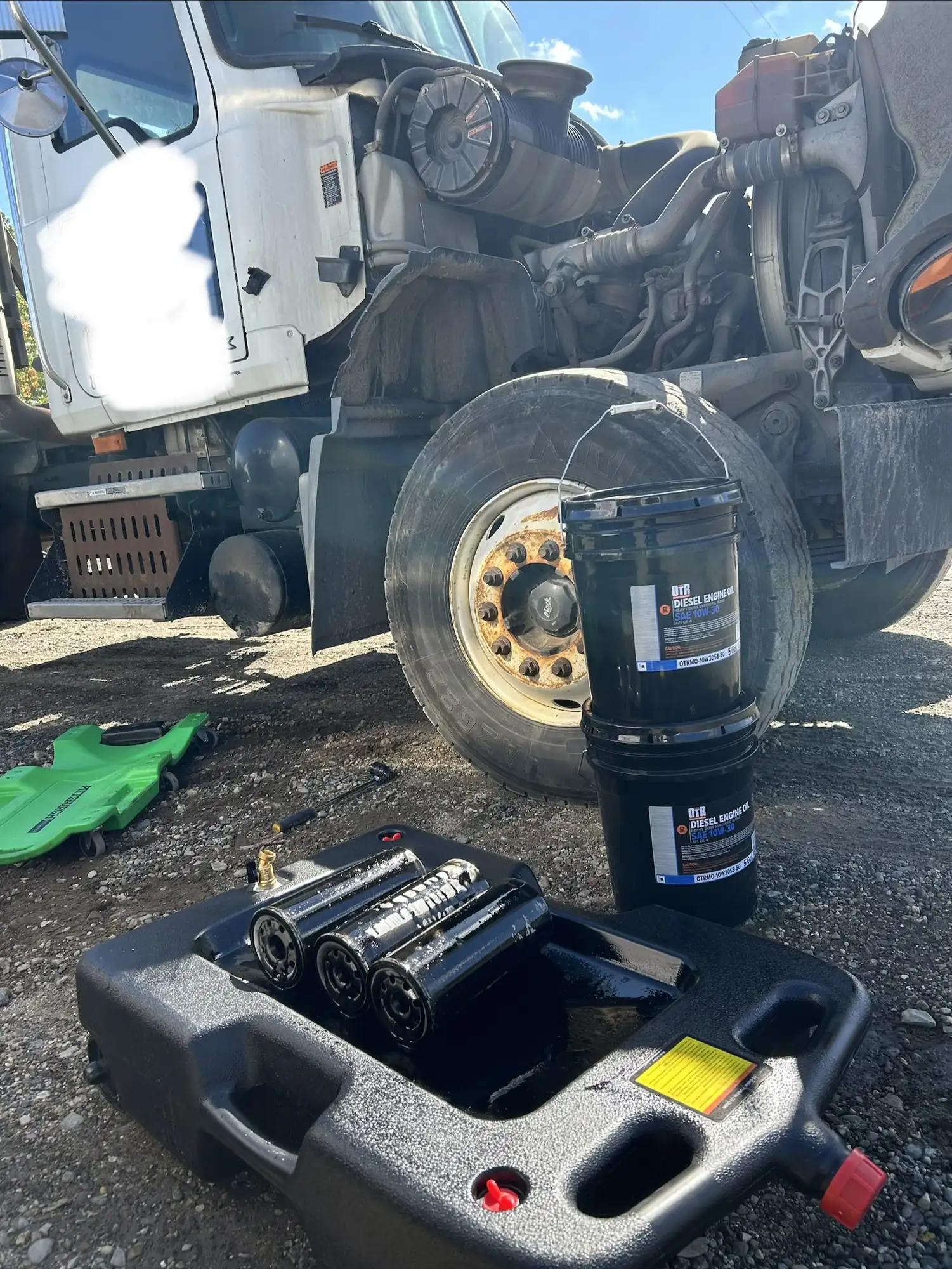 New oil filters and drain pan set up beside a semi truck