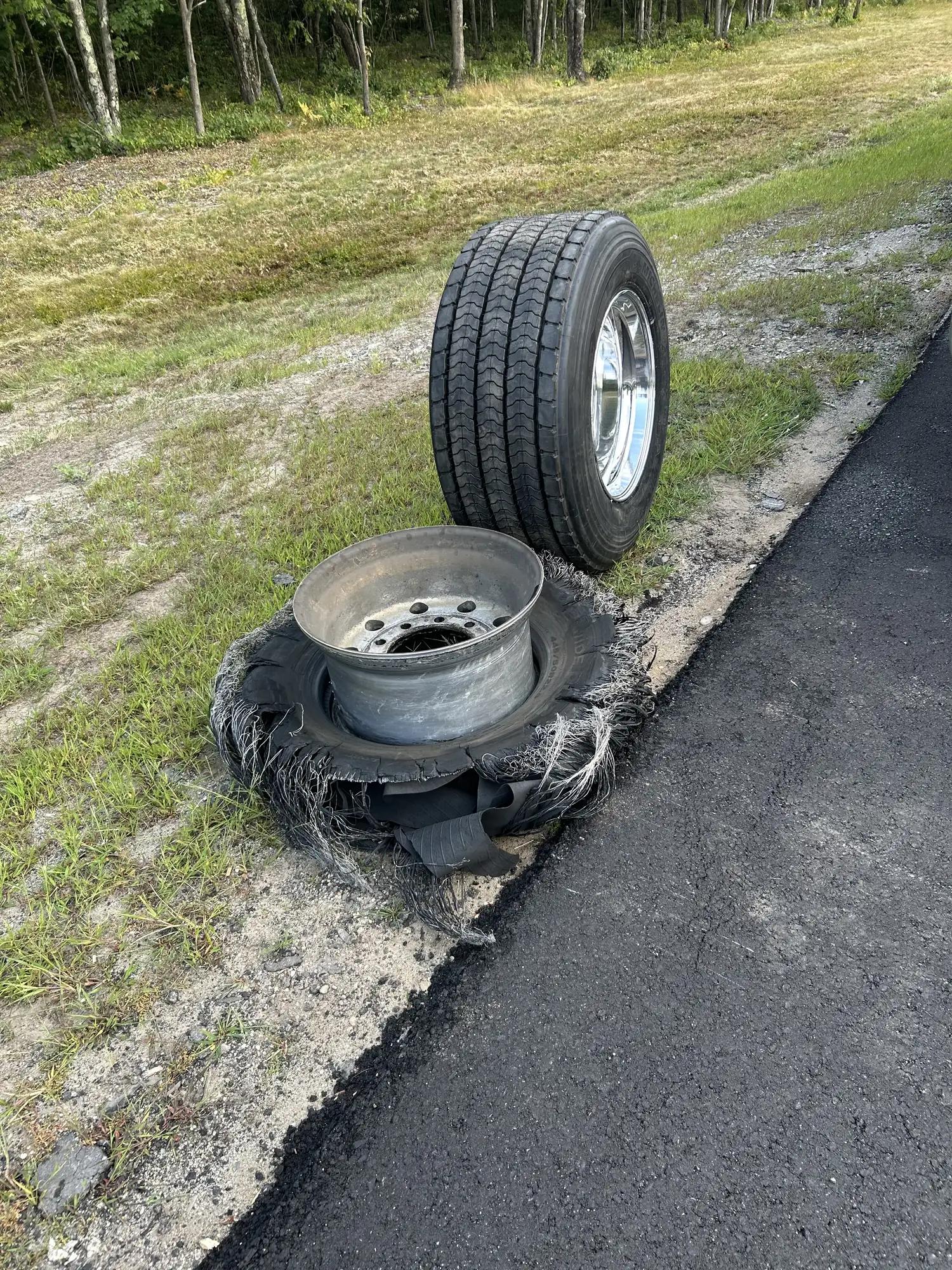 Shredded trailer tire beside its replacement on the roadside