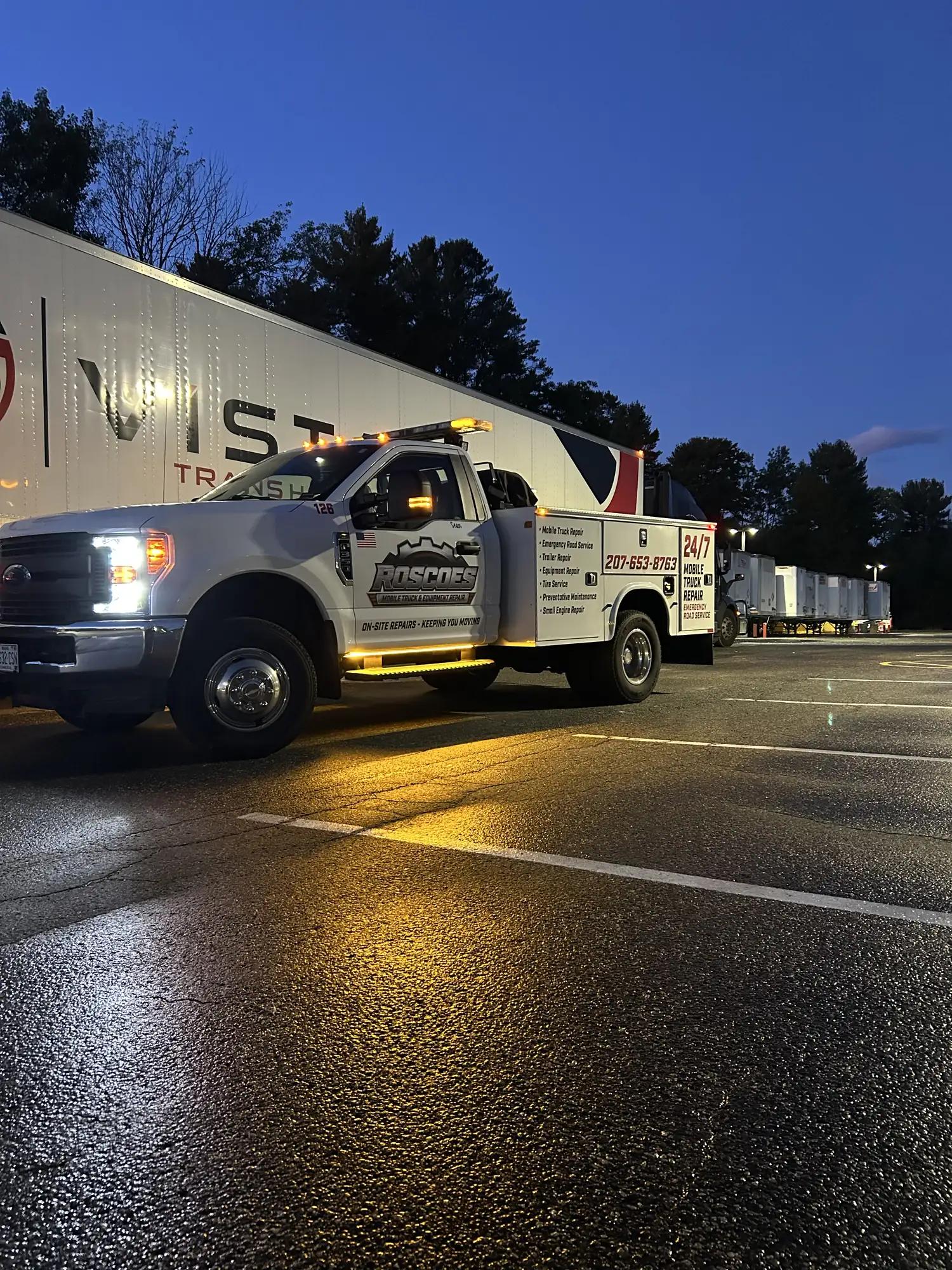 Service truck with lights on beside a fleet truck at dusk