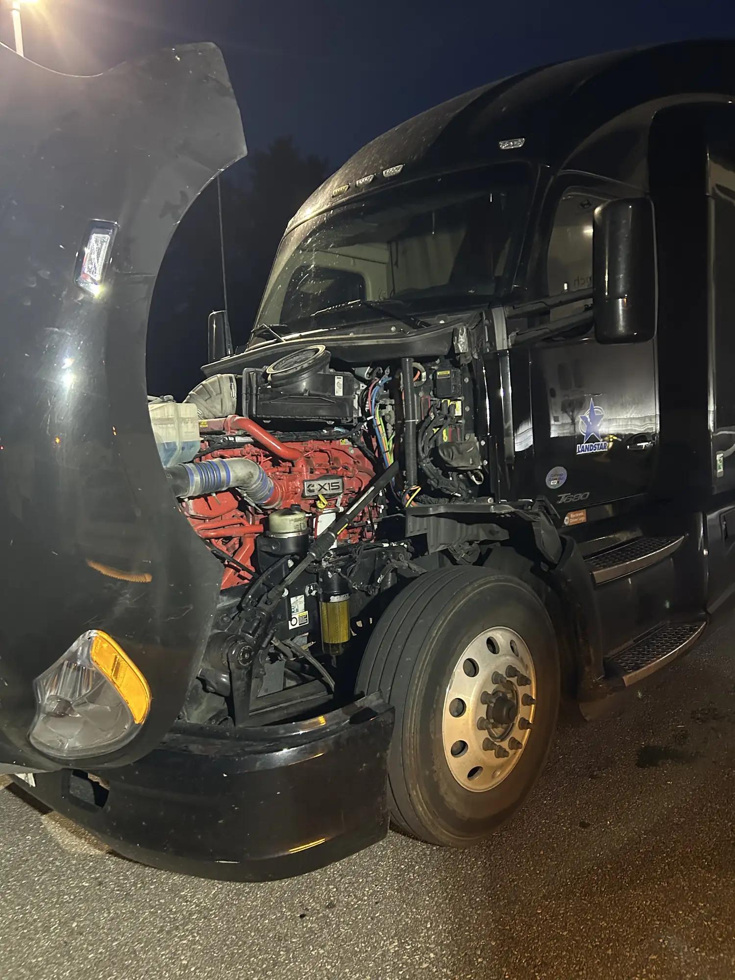 Semi truck with hood open for on-site engine repair at night