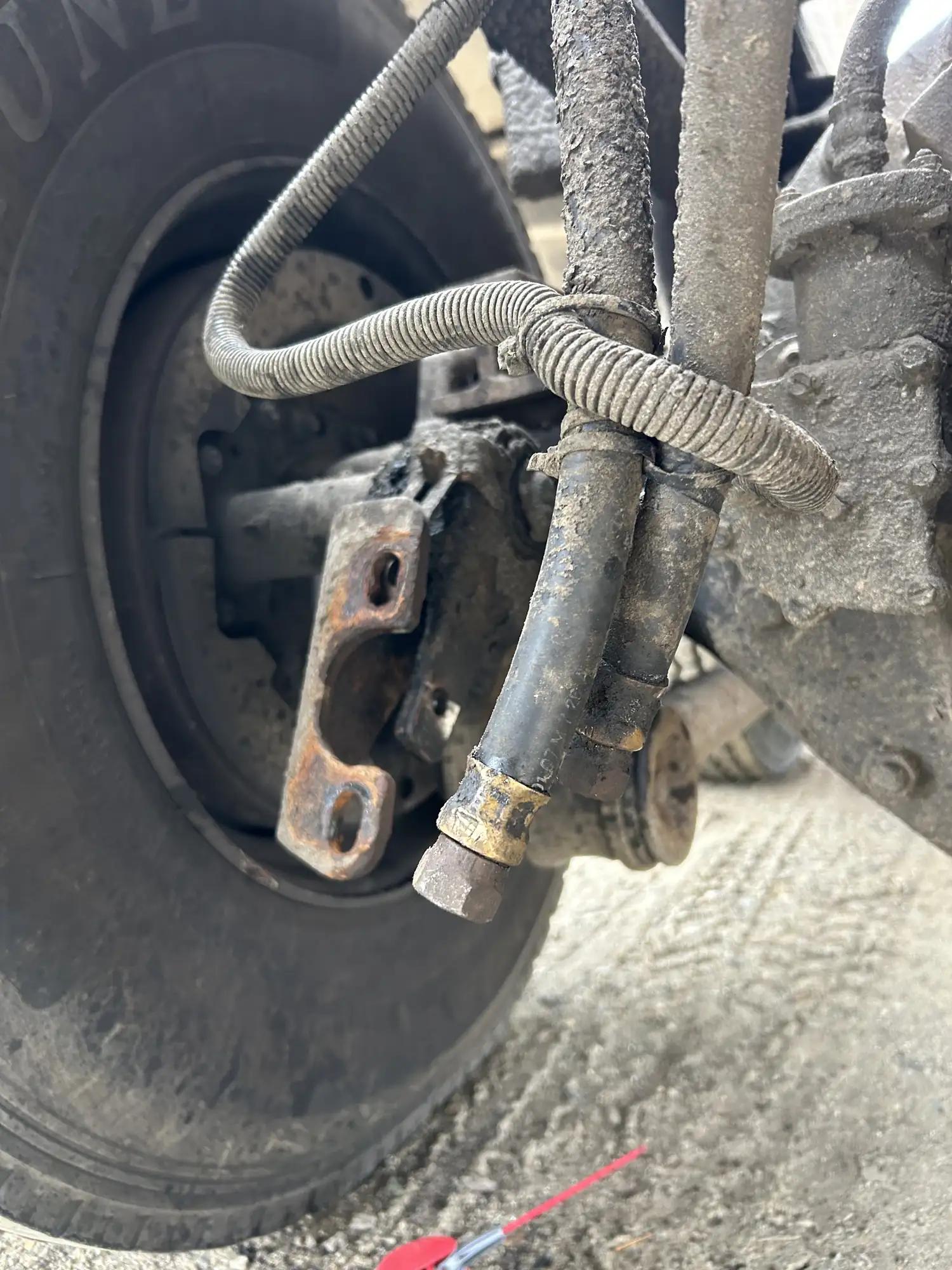Brake chamber and air lines behind a truck wheel before repair