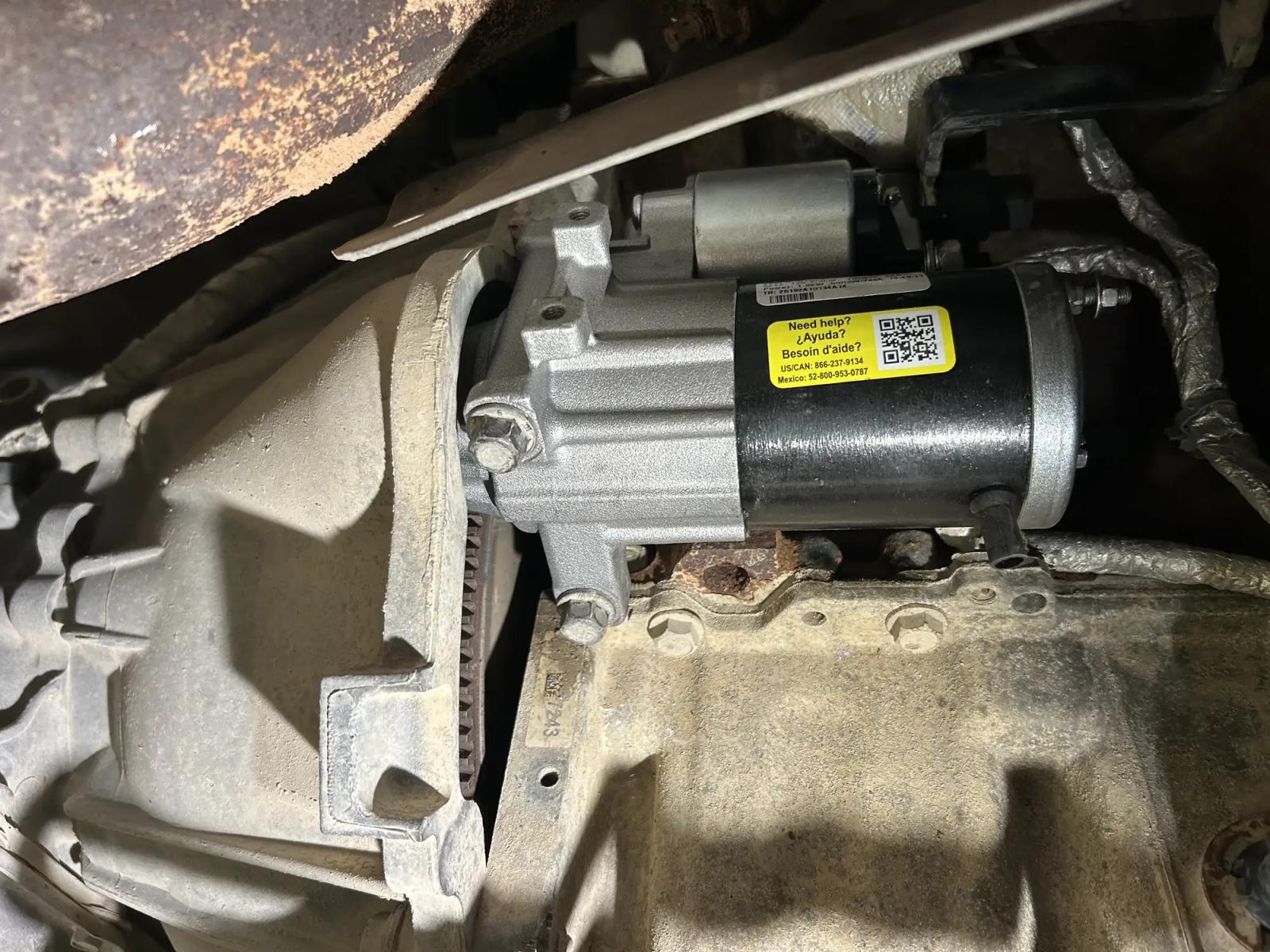 New starter motor mounted on a truck engine bellhousing