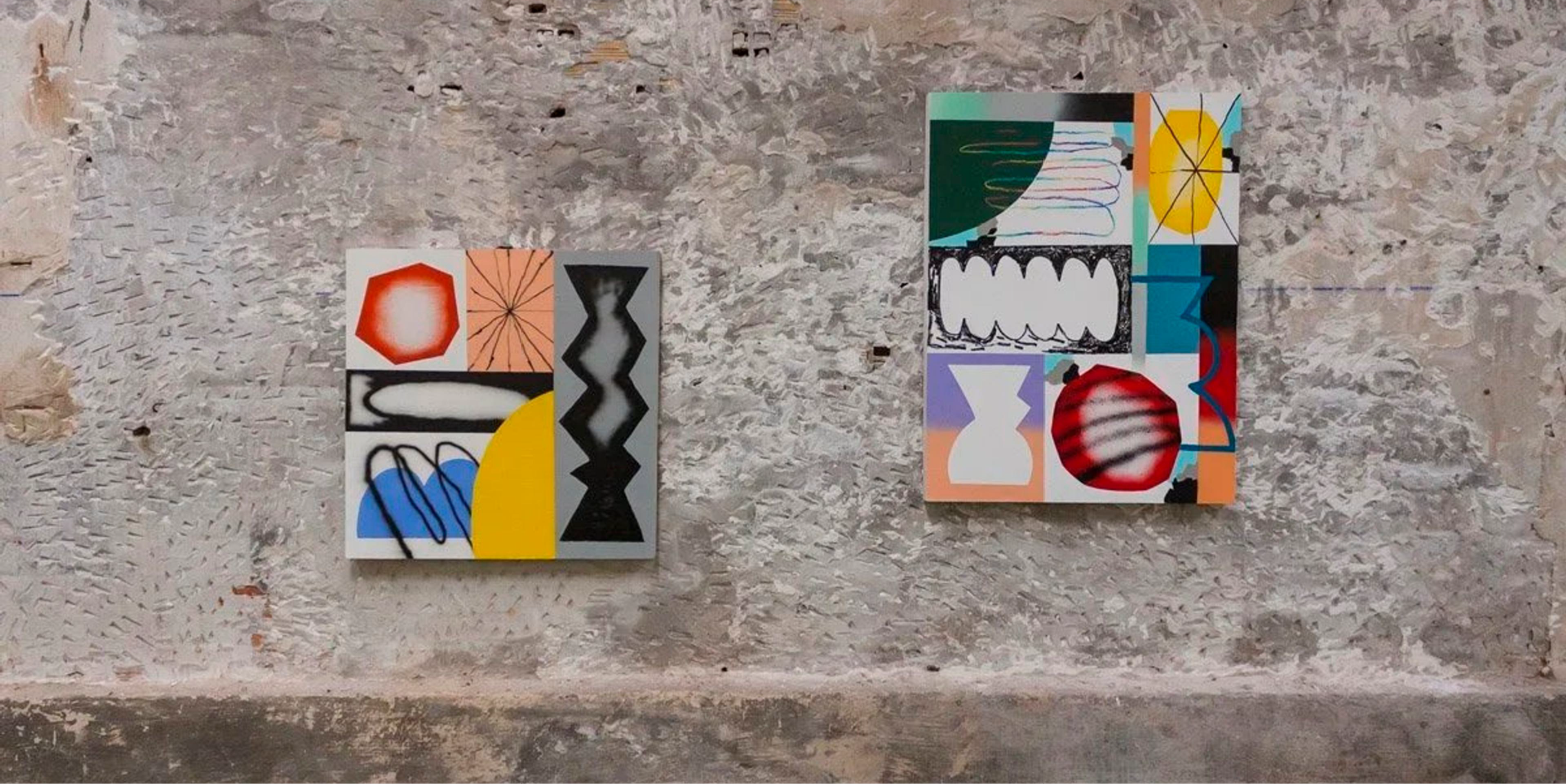 Two colourful geometric paintings hanging on a weathered stone wall at the Hypershapes exhibition.