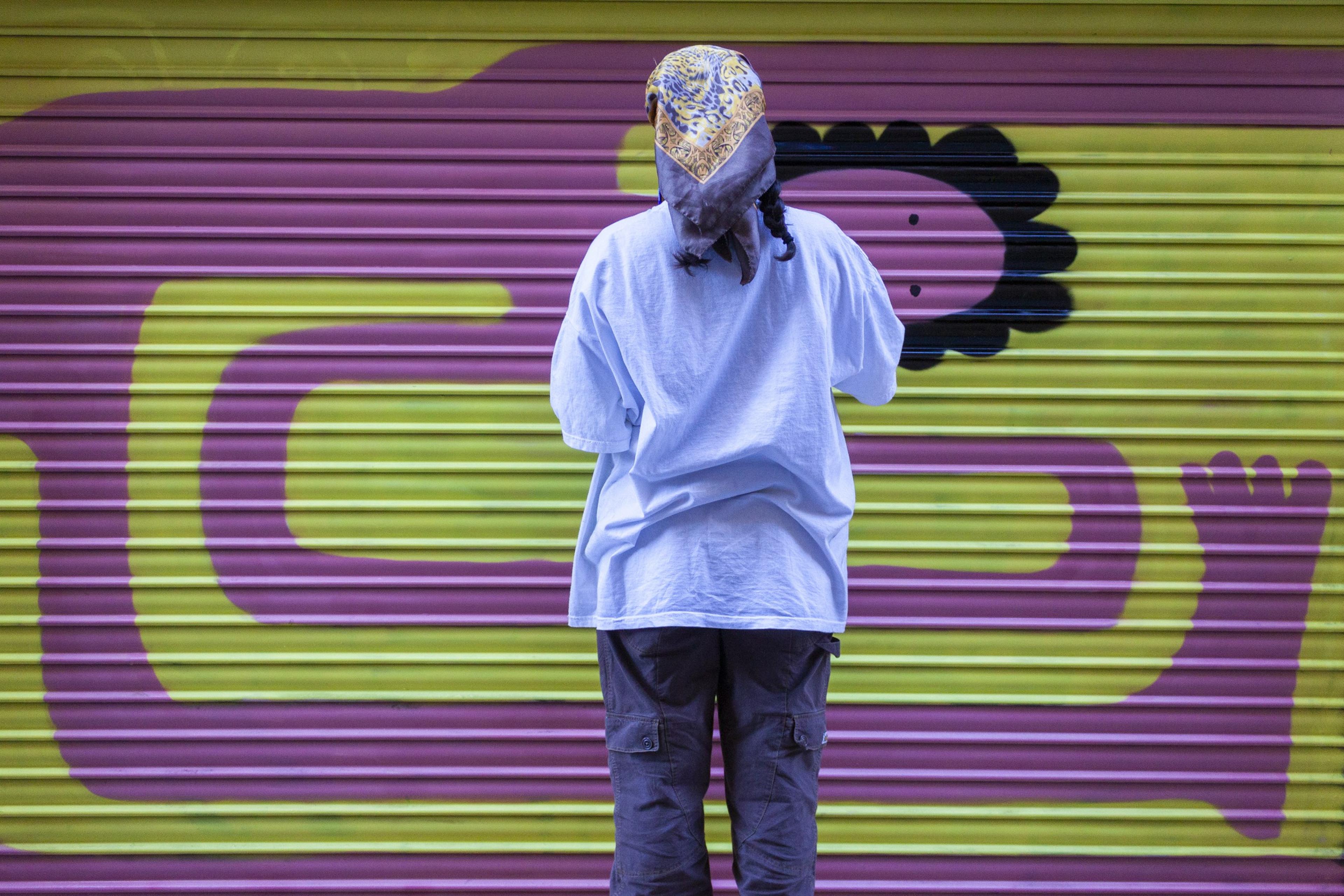 Artist painting in front of a colourful shutter mural