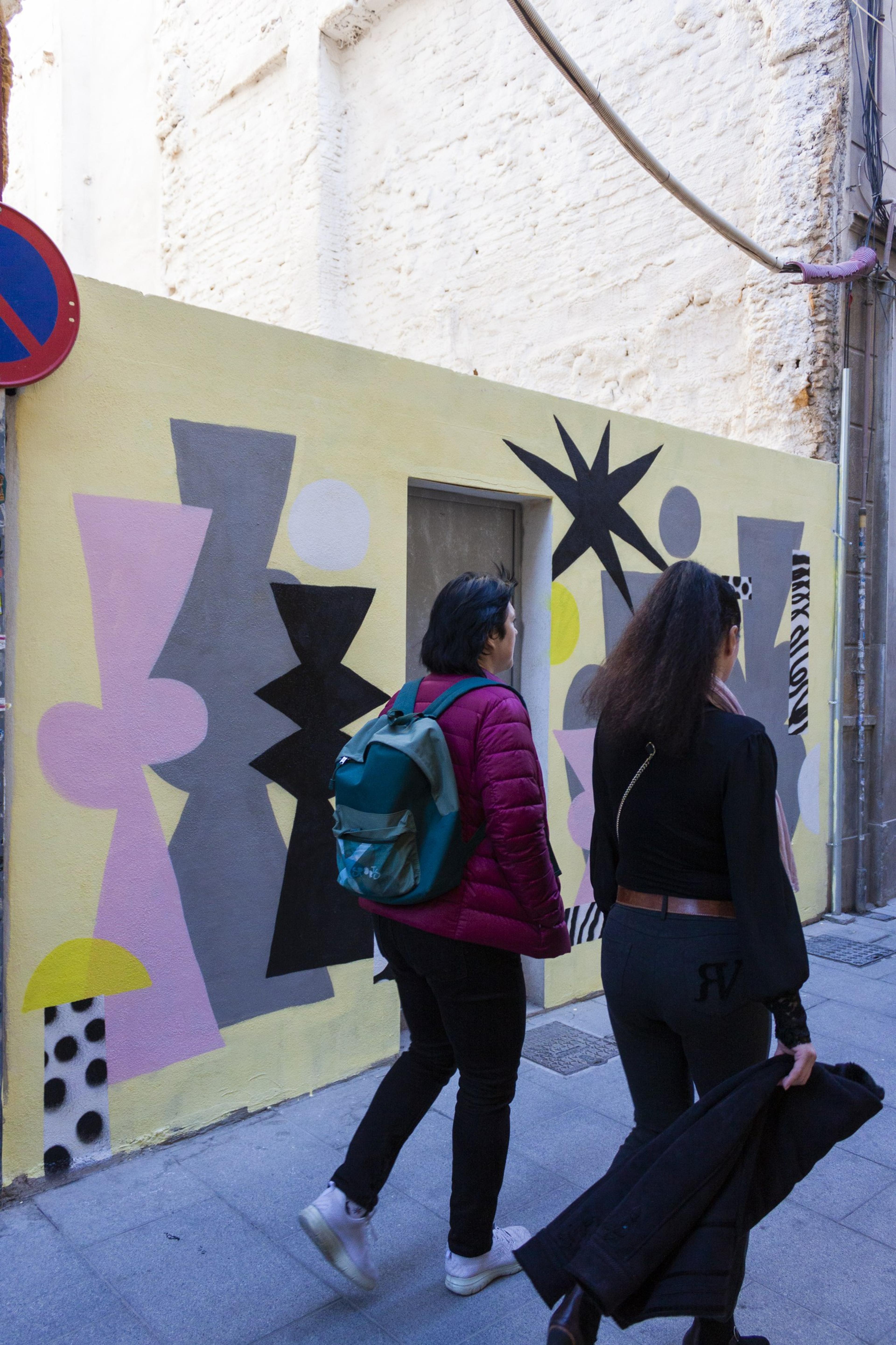 Passers-by in front of a geometric wall painting