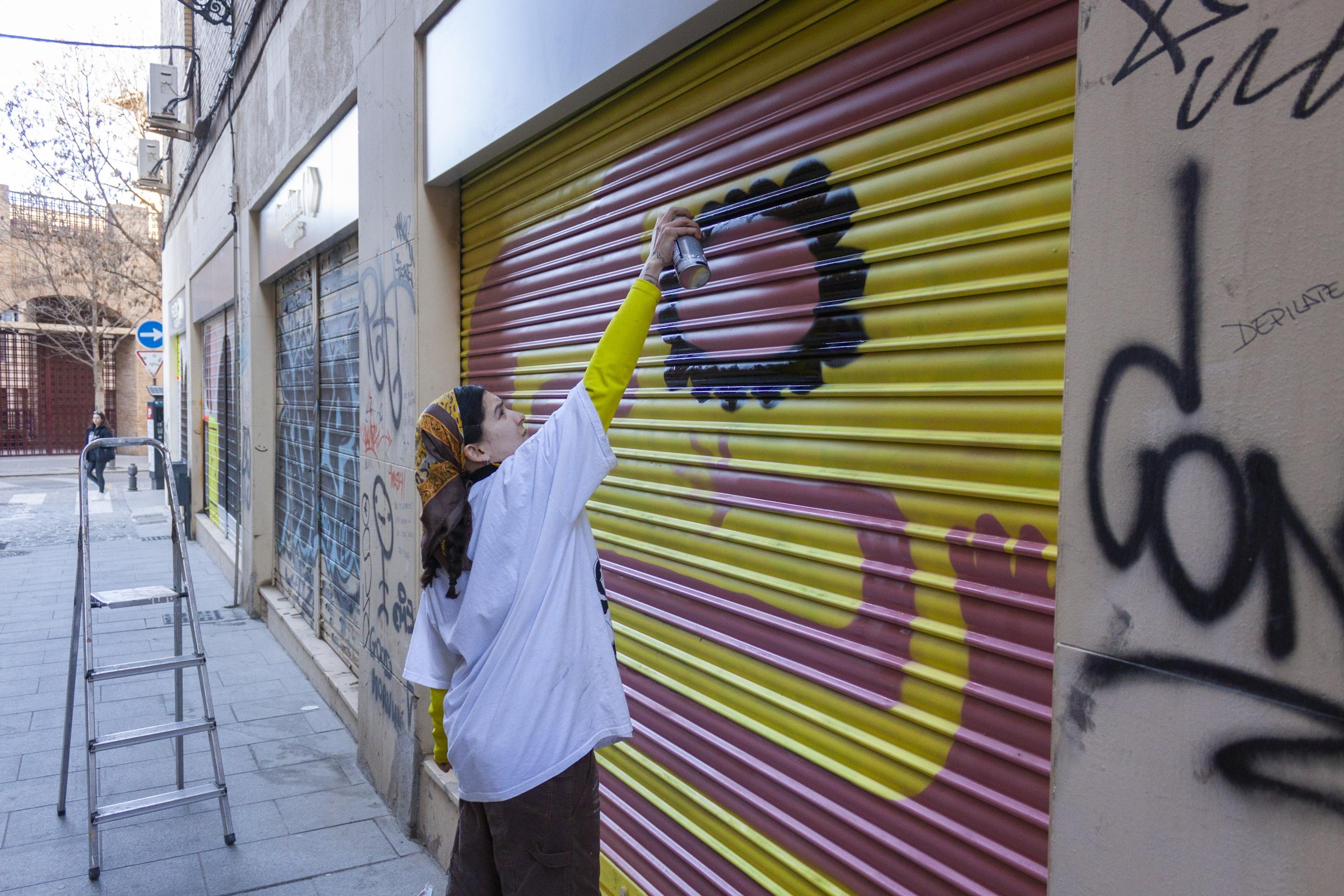 Artist painting a flower on a neighbourhood shutter