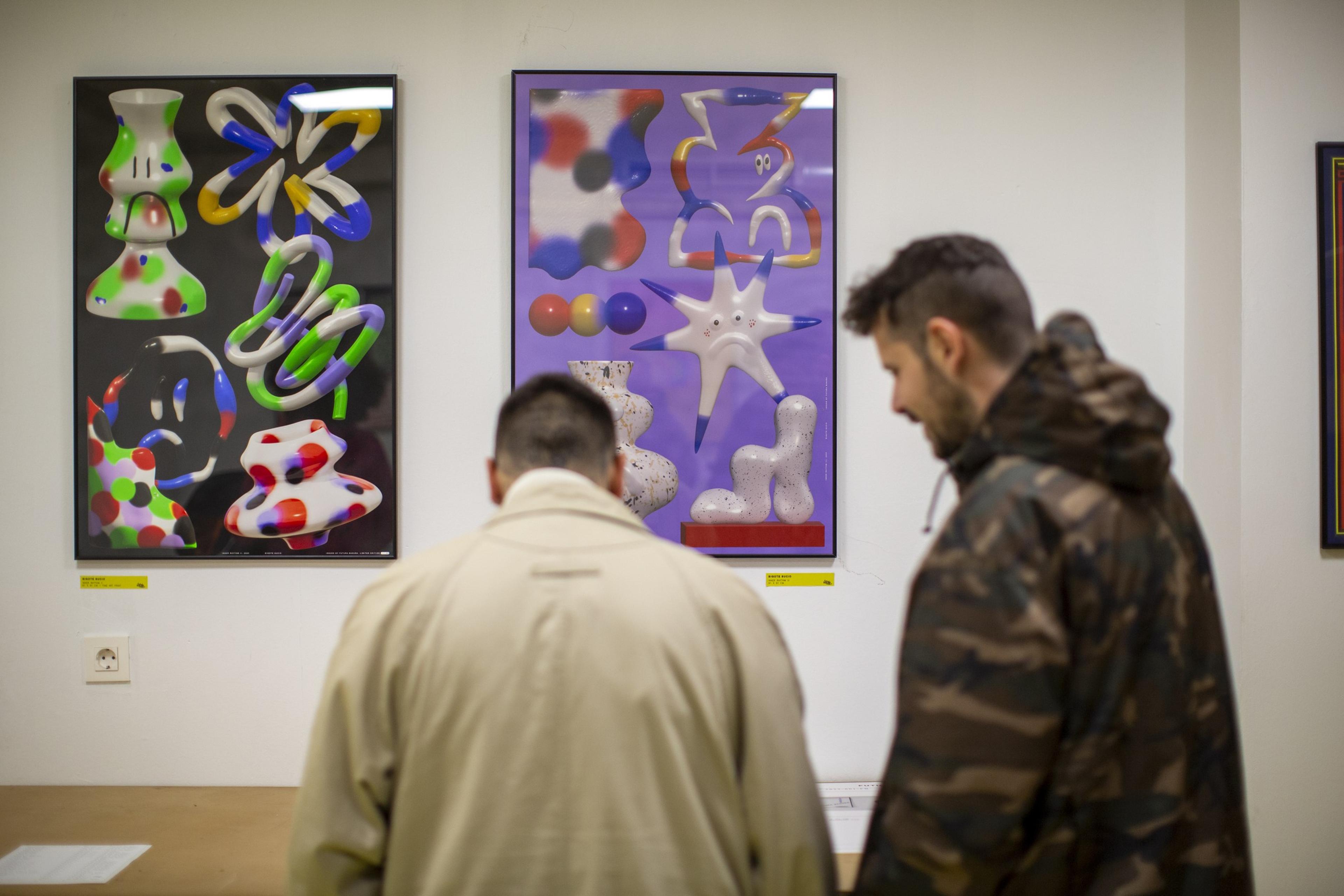 Visitors looking at framed graphic artworks in the exhibition