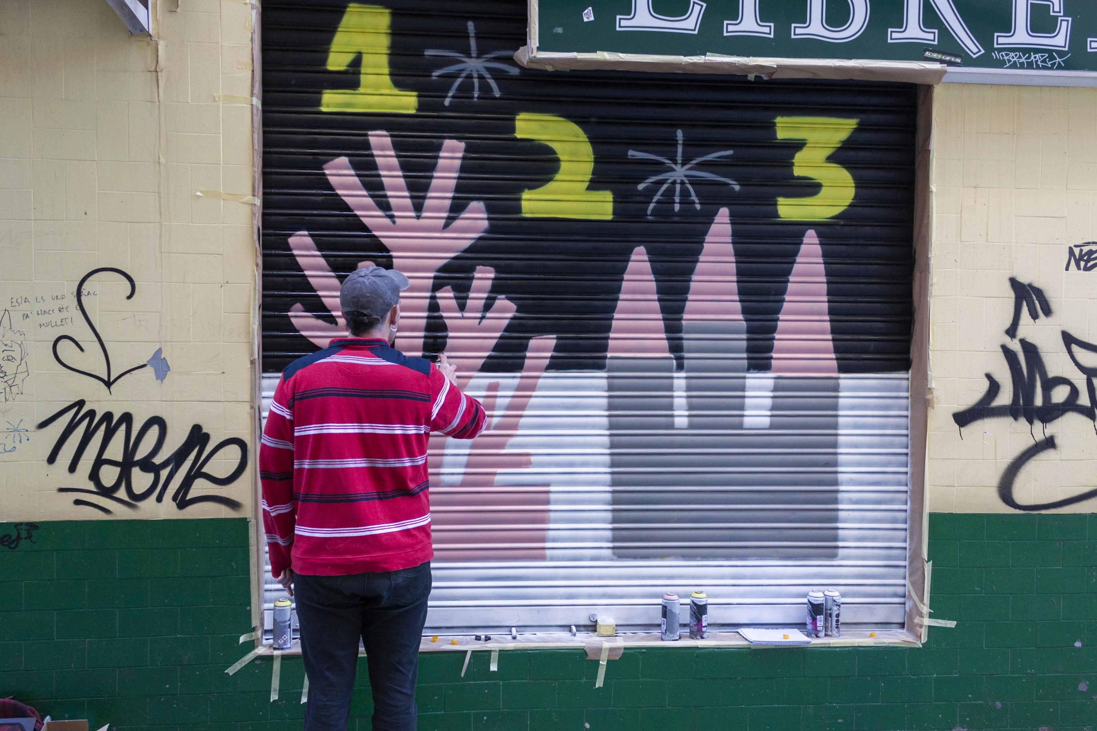 Artist painting a geometric mural on a shutter