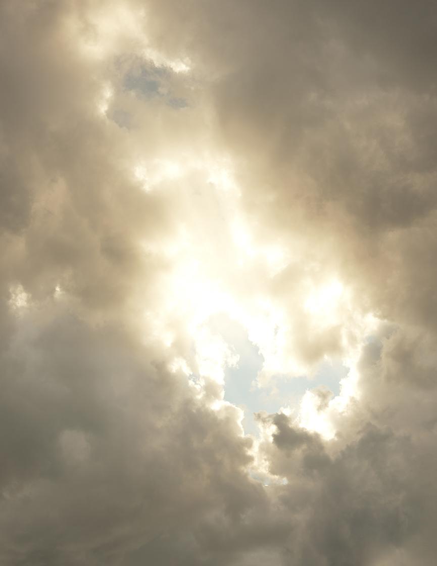 view into the sky with sun behind clouds