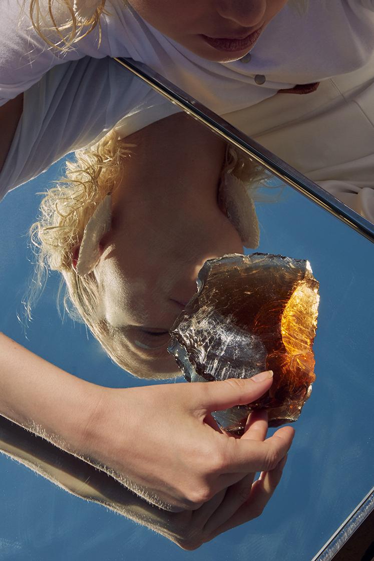 reflection of a female model from the bottom holding gemstone