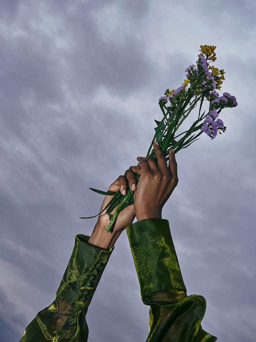 2 hands holding flowers towards the sky