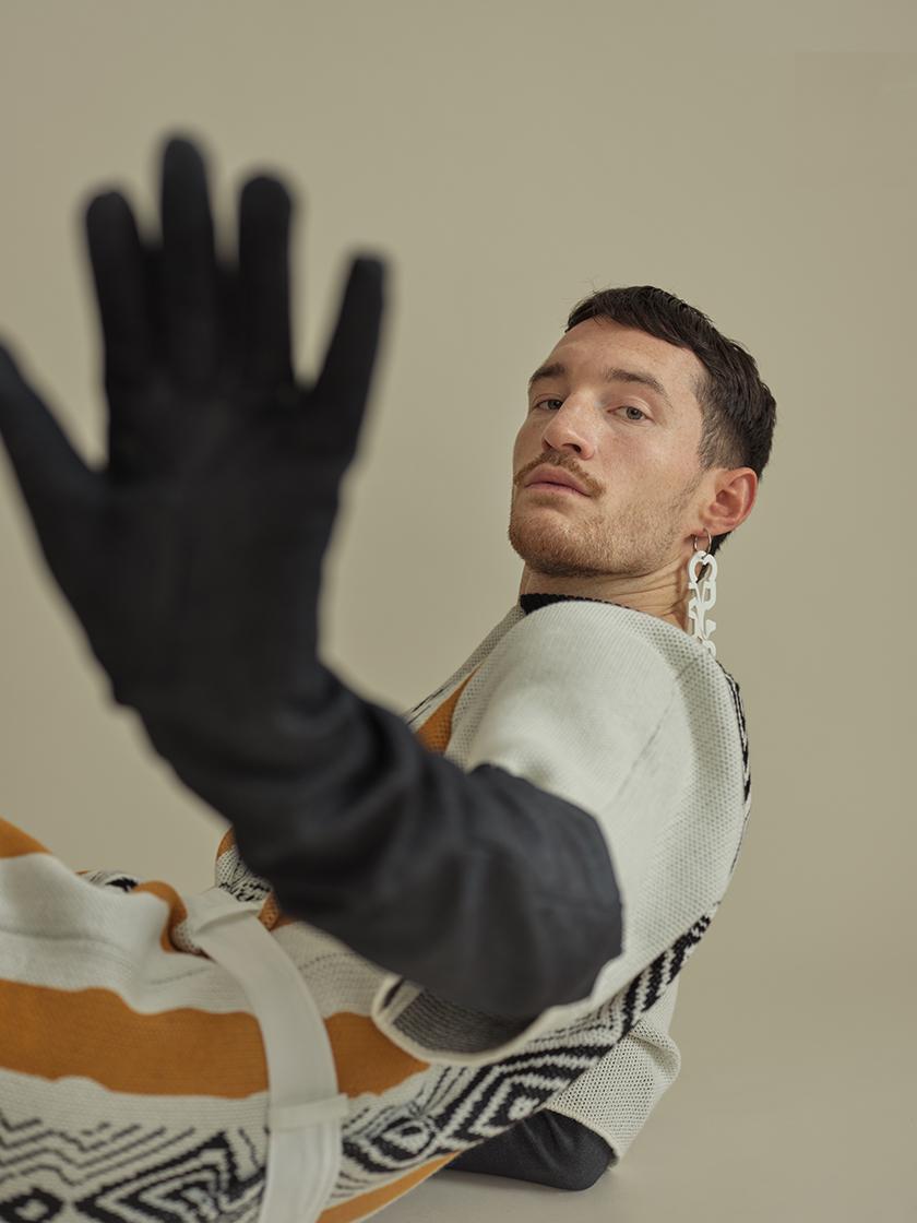 male model holds glove in the camera
