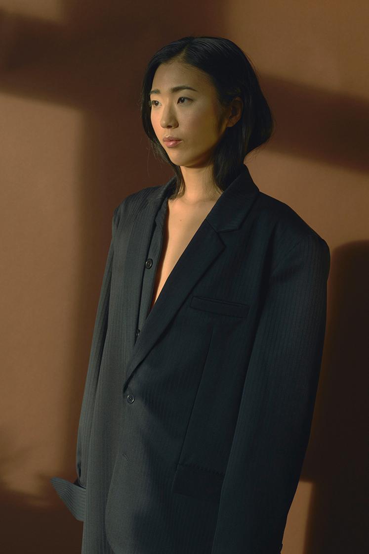 female model in front of brown wall and light reflection
