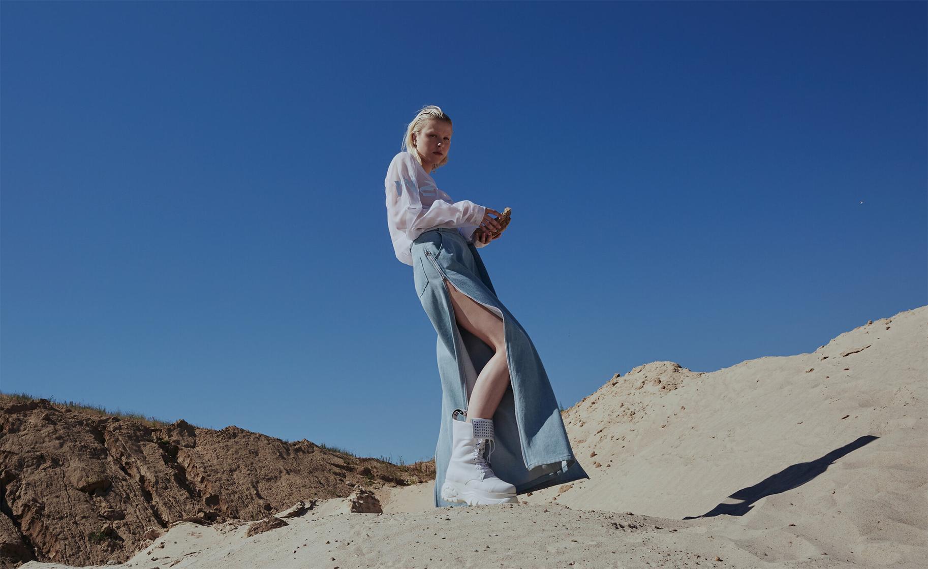 female model standing on sand dune