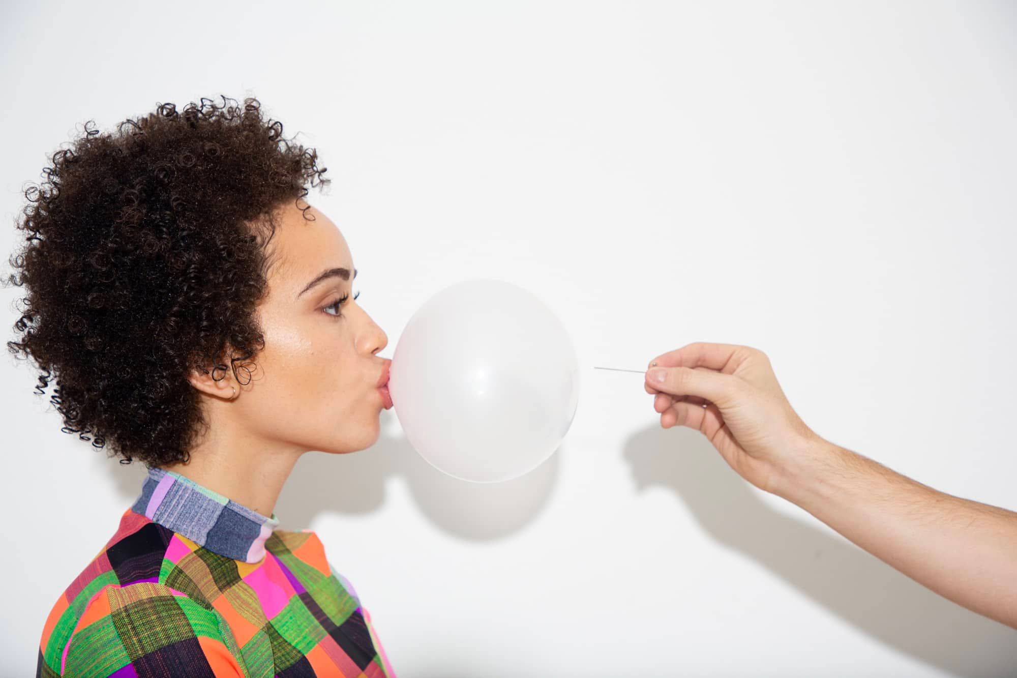 portrait photography of girl with curly hair popping bubble