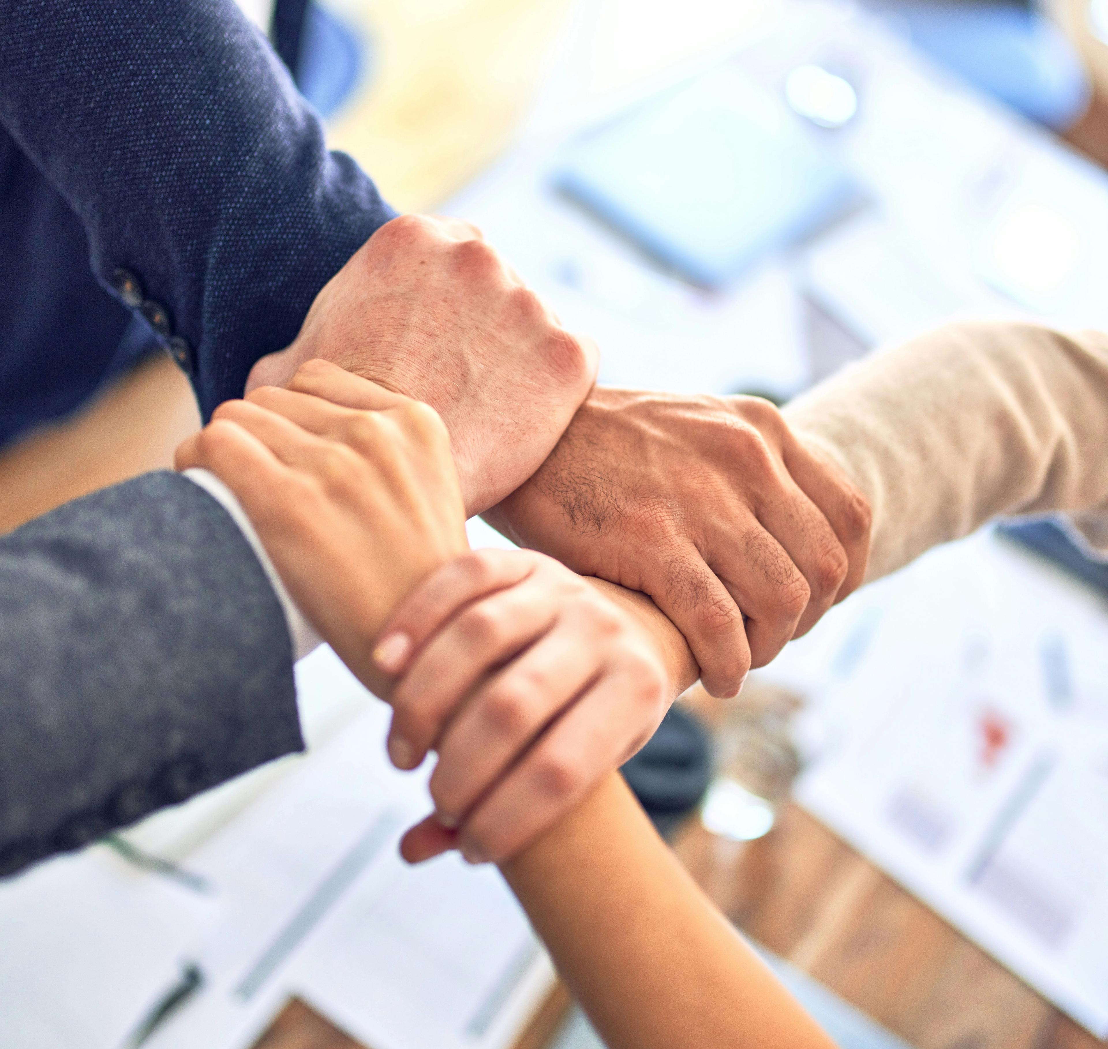 4 hands grasping in a sign of unity