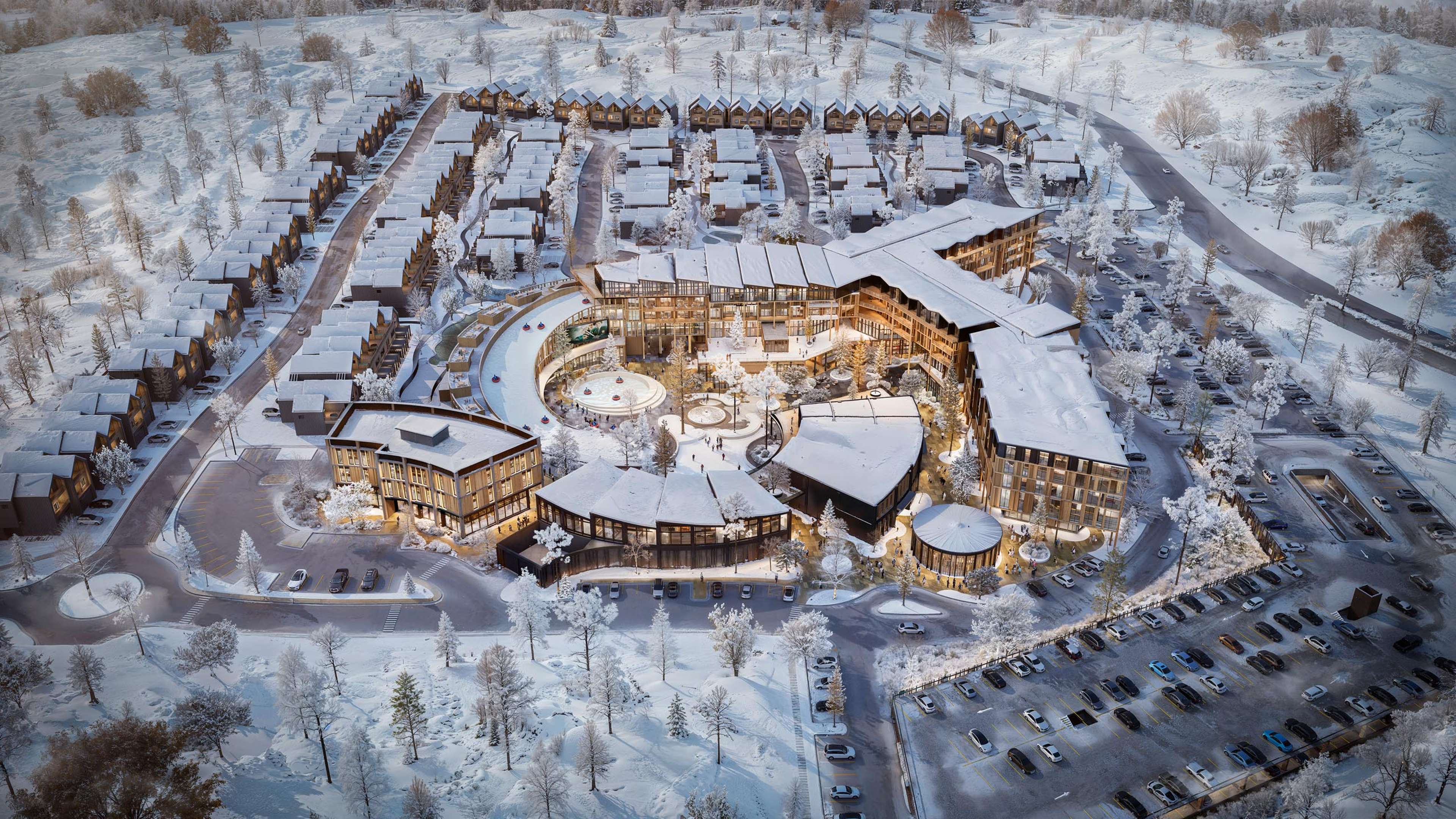 Aerial view of a modern, snow-covered resort complex with a large central hotel and surrounding residential community.