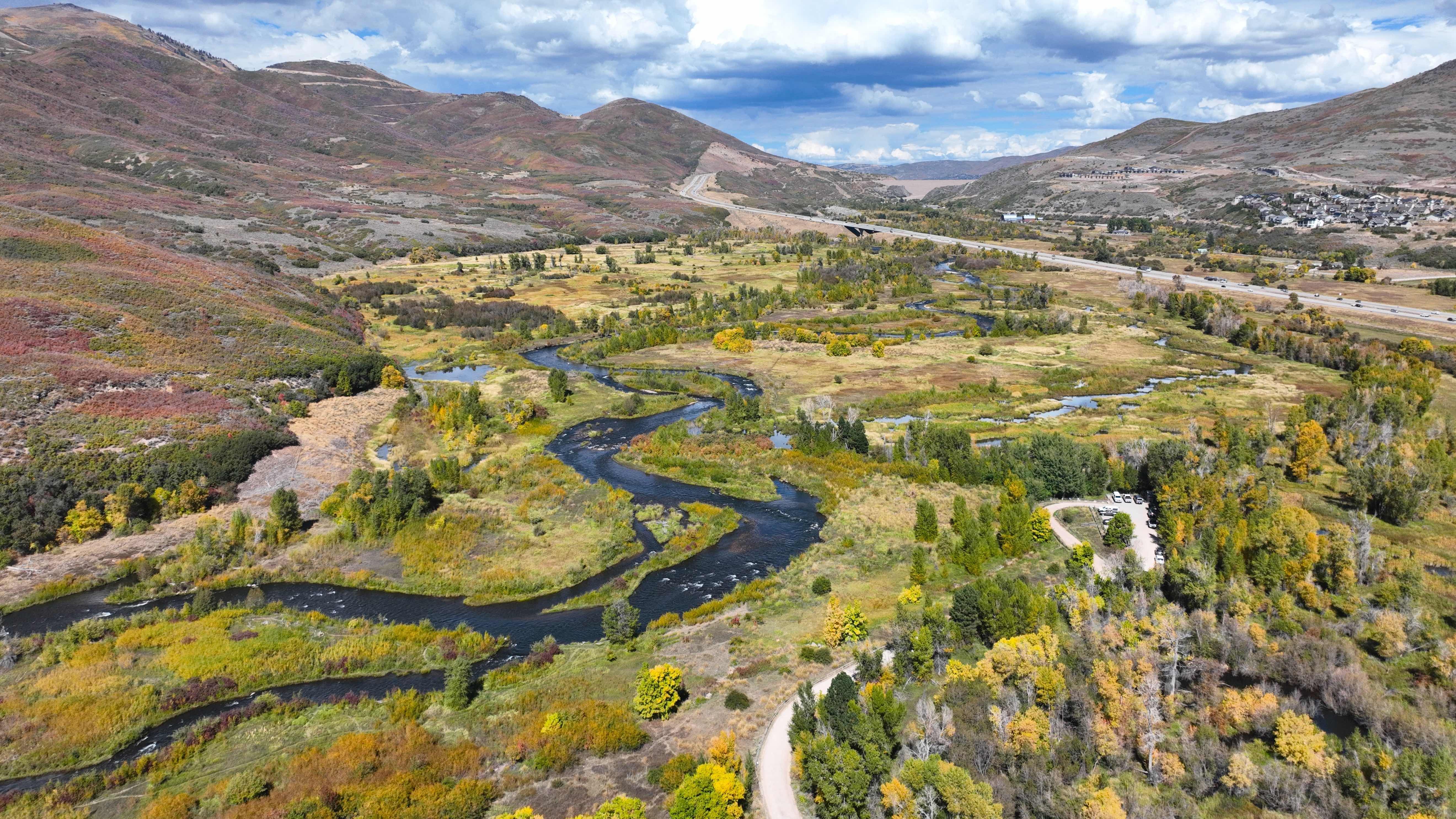 View of provo river with mountains and trees and a blue sky with clouds