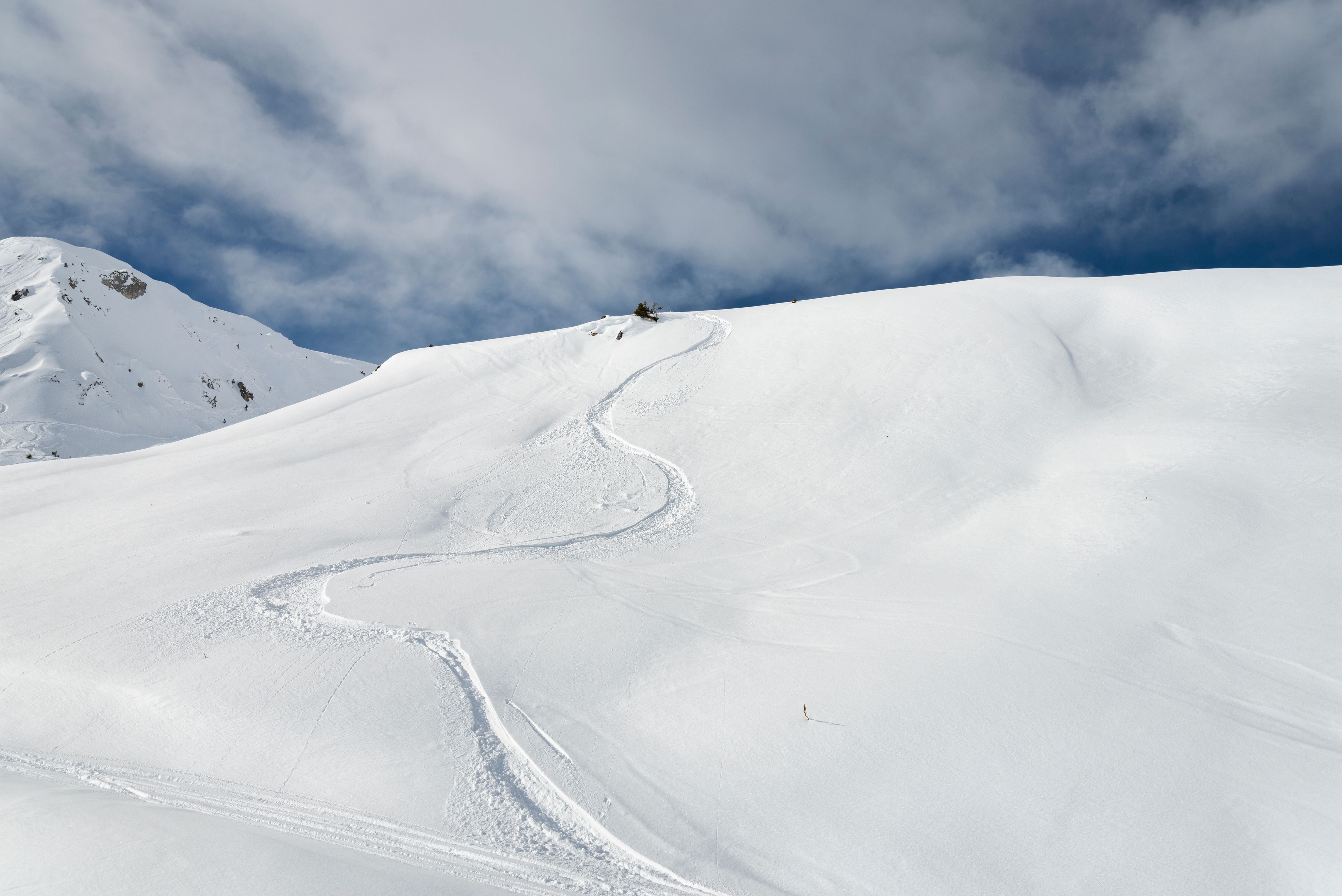 snow covered mountain with one skier and blue sky