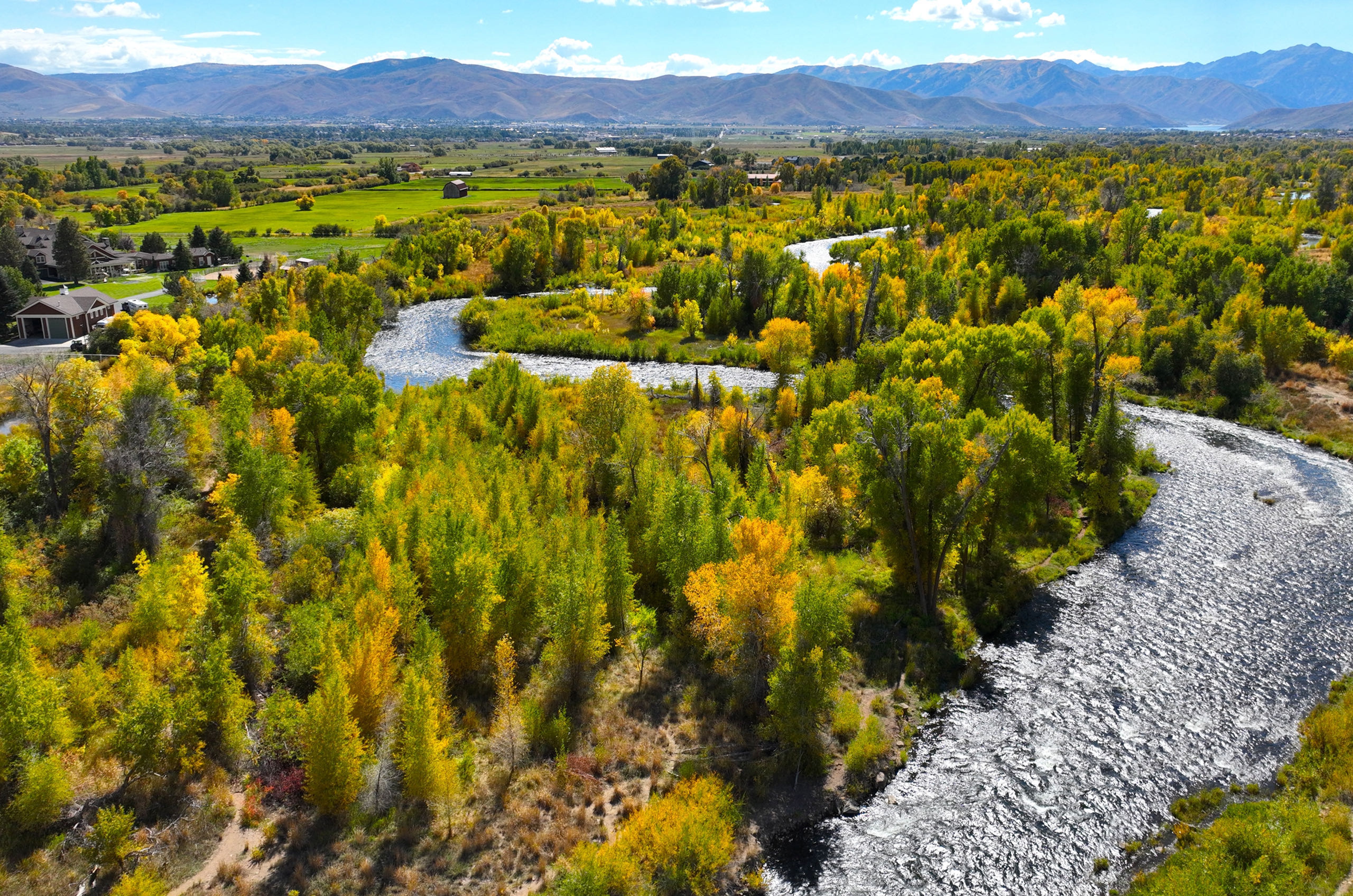 view of the provo river surrounded by trees mountains and blue sky in heber valley utah