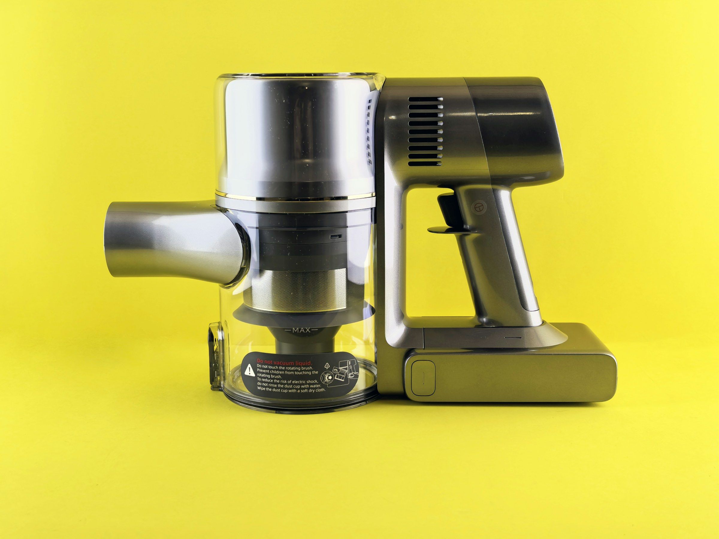 A cordless stick vacuum body against a bright yellow backdrop