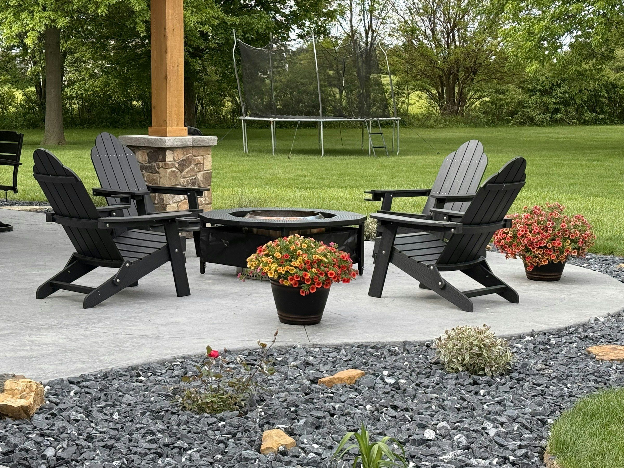 Backyard patio with Adirondack chairs around a fire pit and potted flowers