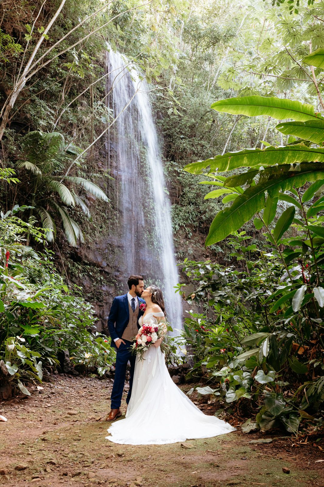 Bride and groom in front of a waterfall on Kauaʻi