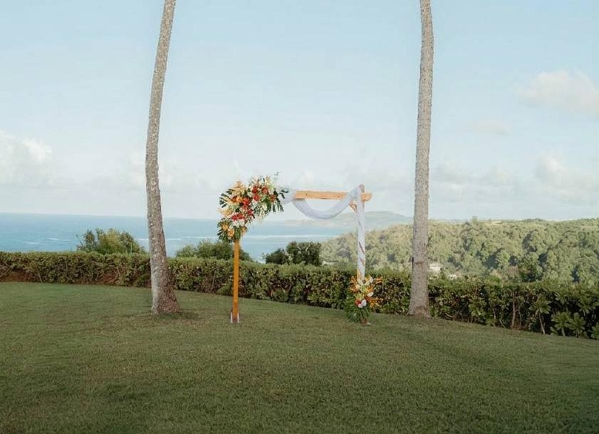 Wooden wedding arch with tropical florals on an ocean-view lawn at The Westin Princeville