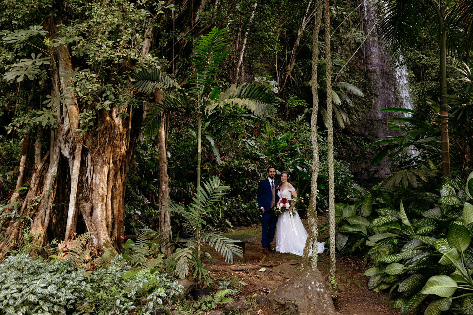 Bride and groom in the jungle with a waterfall in the background on Kauaʻi