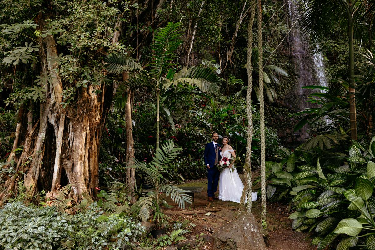 Bride and groom in the jungle with a waterfall in the background on Kauaʻi