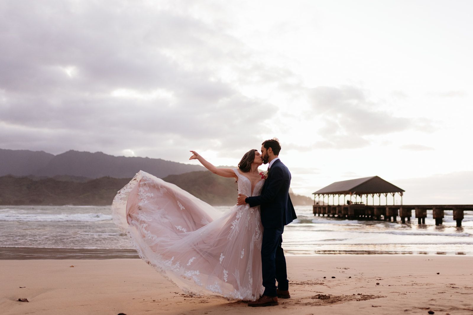 Bride and groom on Hanalei Beach with Hanalei Pier