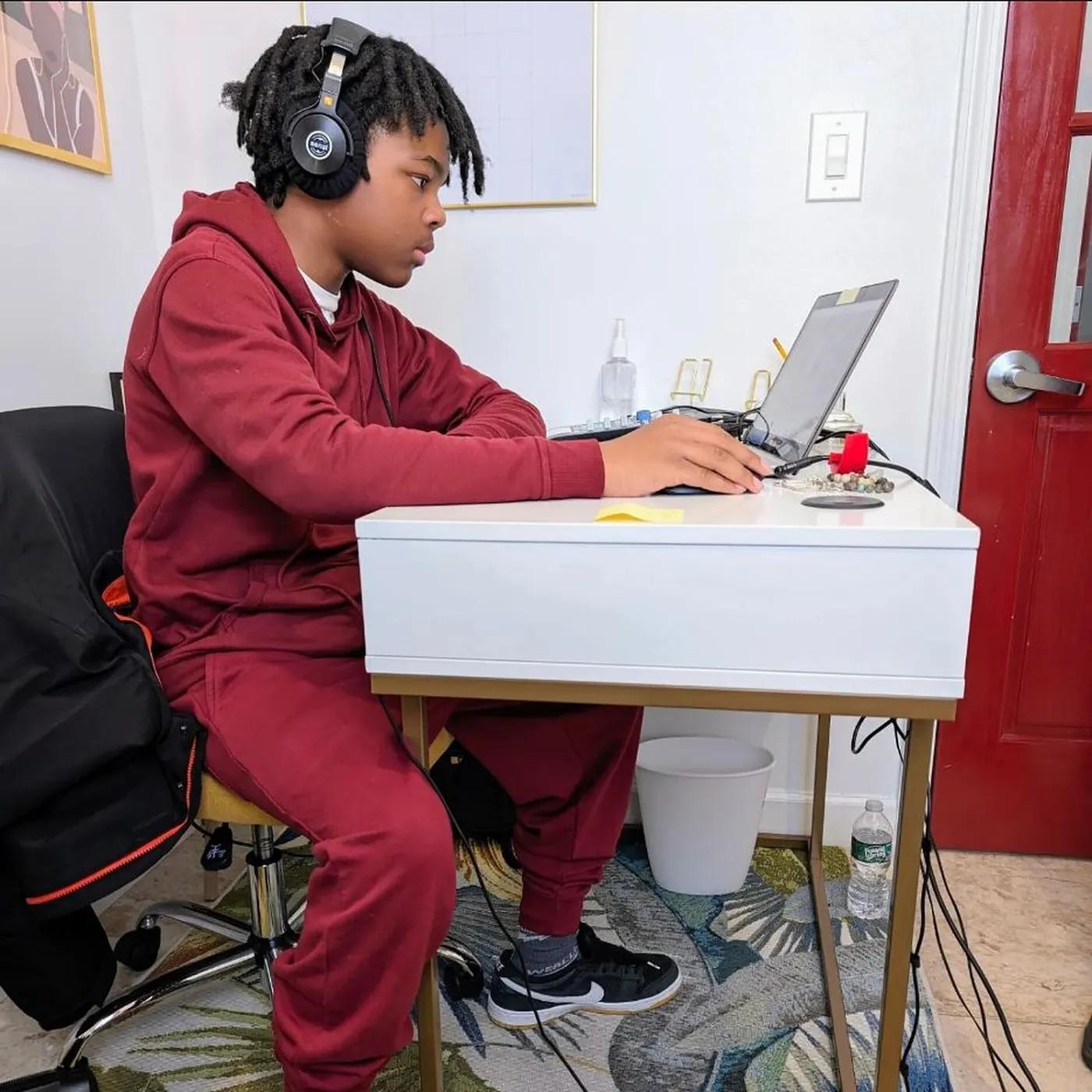 A student working at a laptop with headphones on