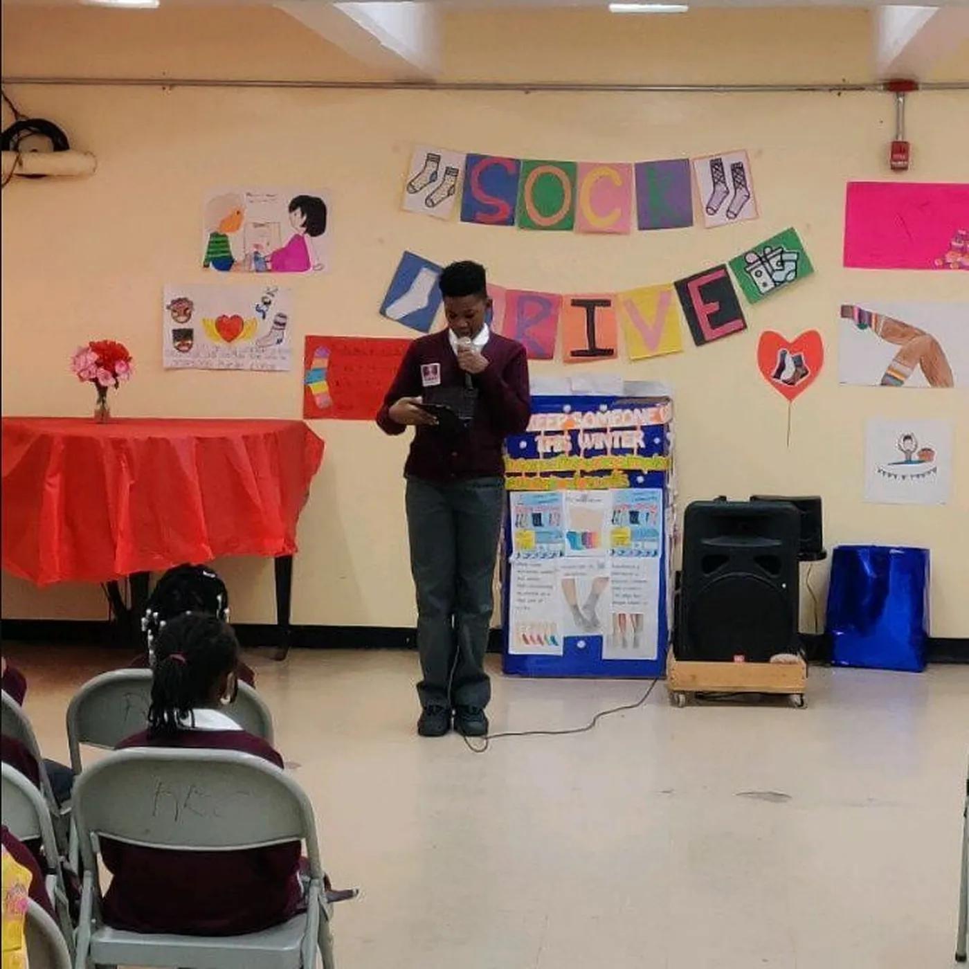 A student speaking at the microphone in front of the school
