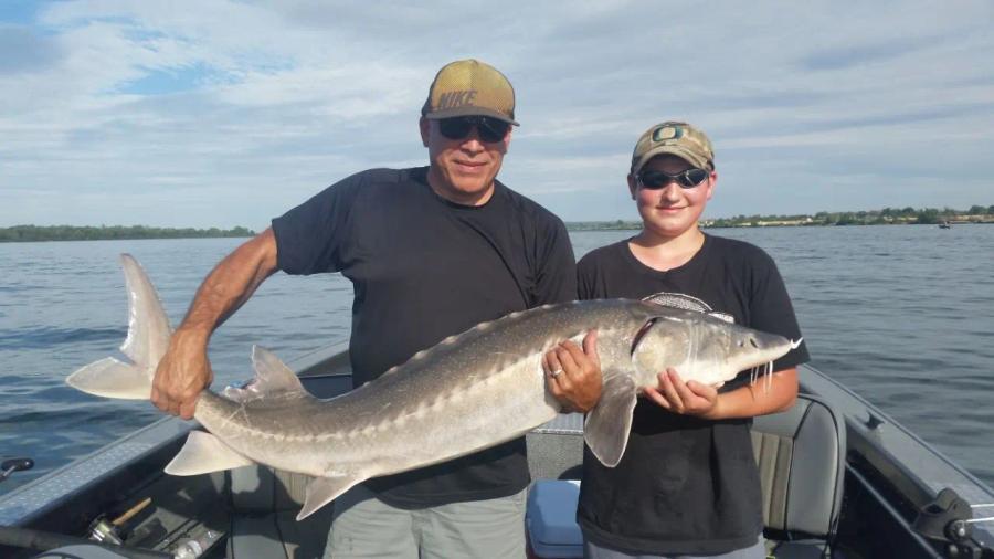 Family group holding a large sturgeon
